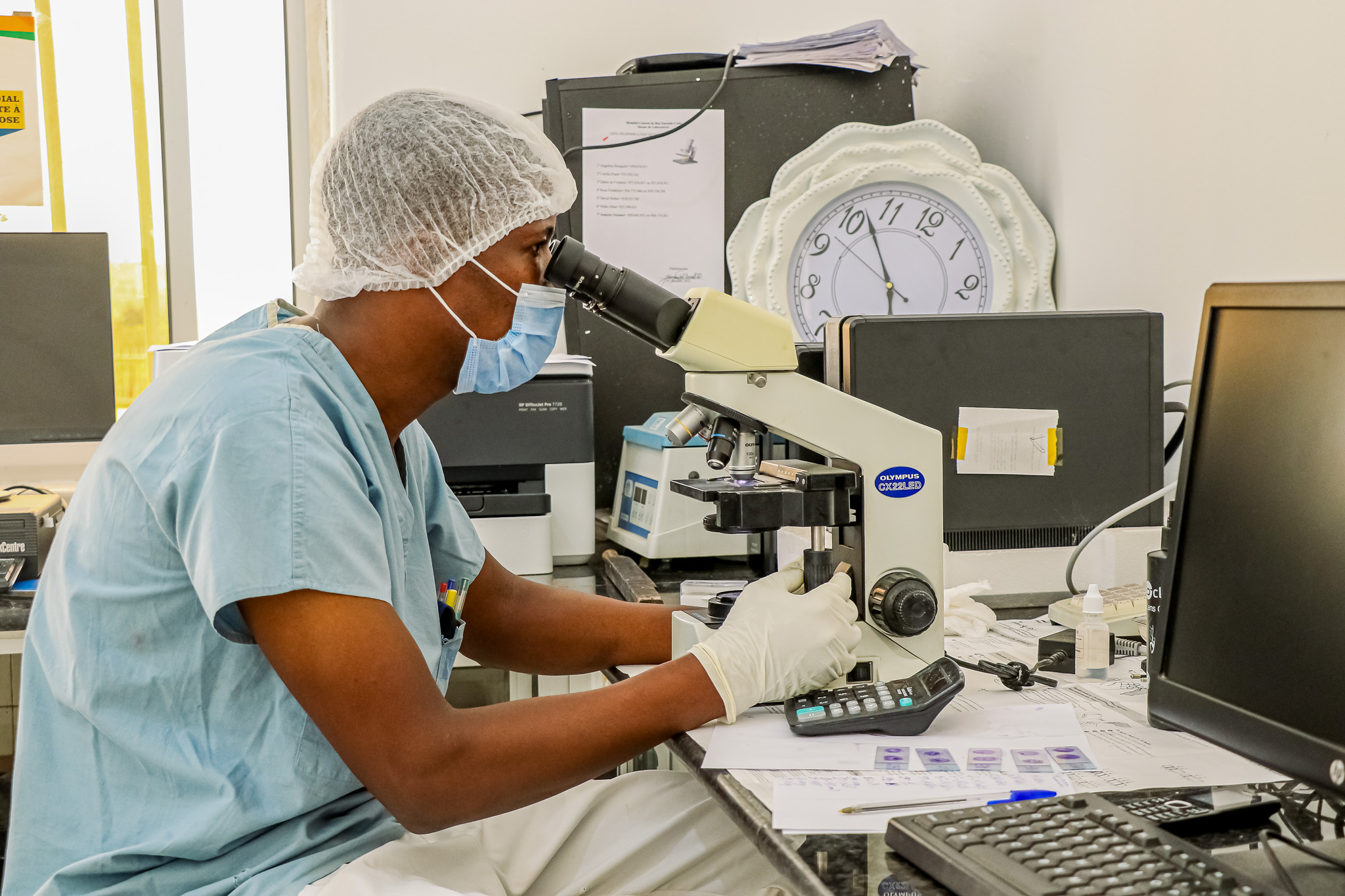 A lab technician looking through a microscope