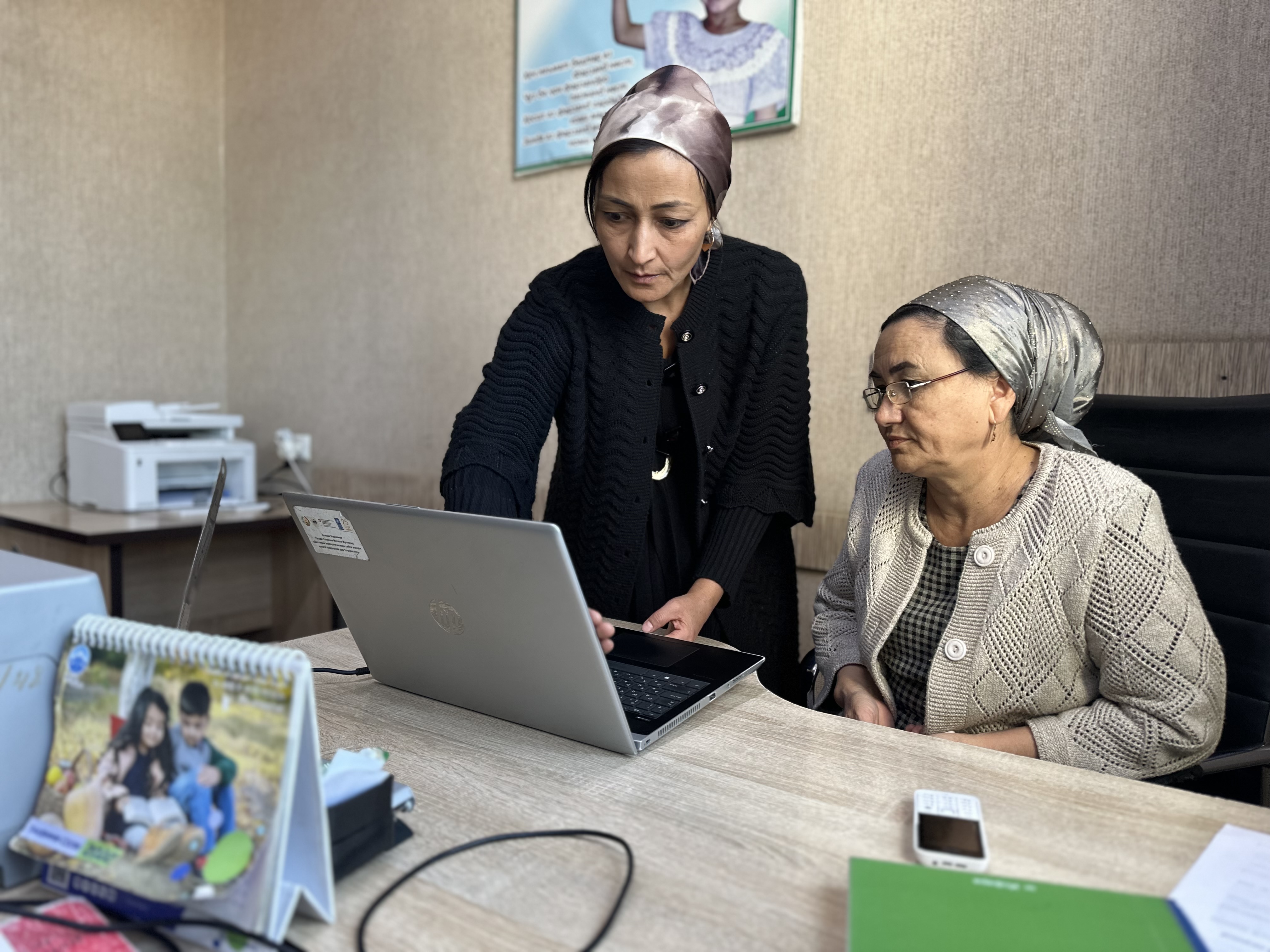Two female employees at the Civil Registry Centre in Isfara, Tajikistan, are inputting data into an online platform.  
