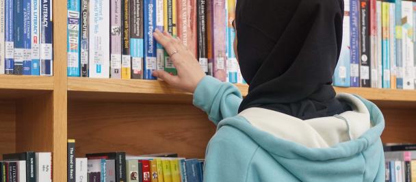 Woman in hijab browses library shelves