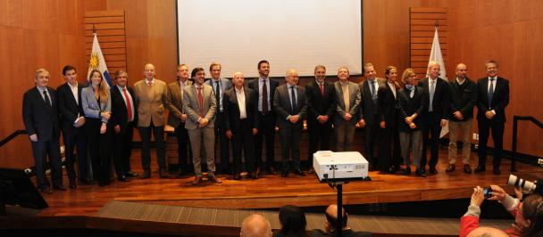 Foto grupal sobre escenario de representantes de todas las instituciones involucradas en el Bono de Impacto Social en Uruguay. 