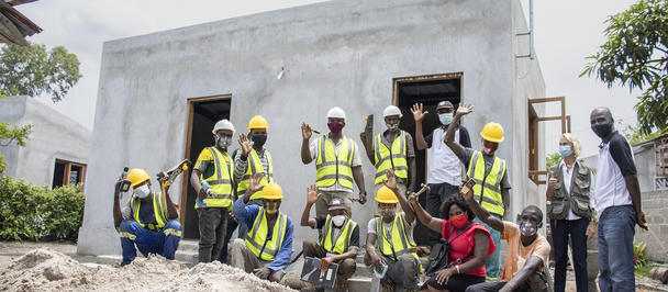 Group of workers on a construction site, in front of a concrete building.