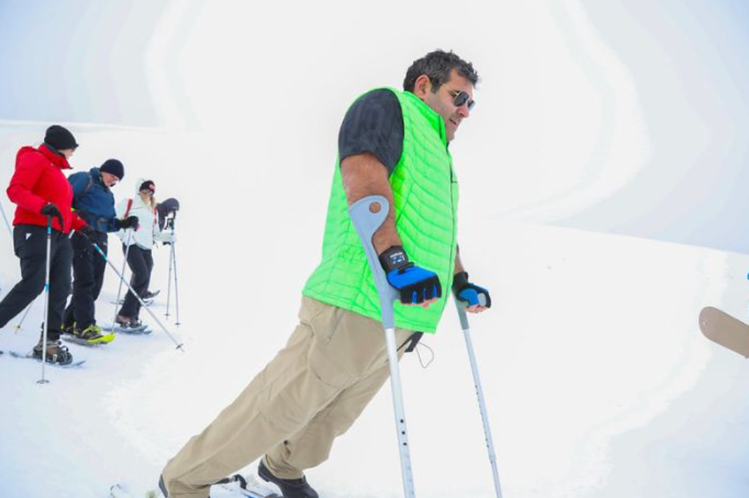 Mann med krykker som går på snø