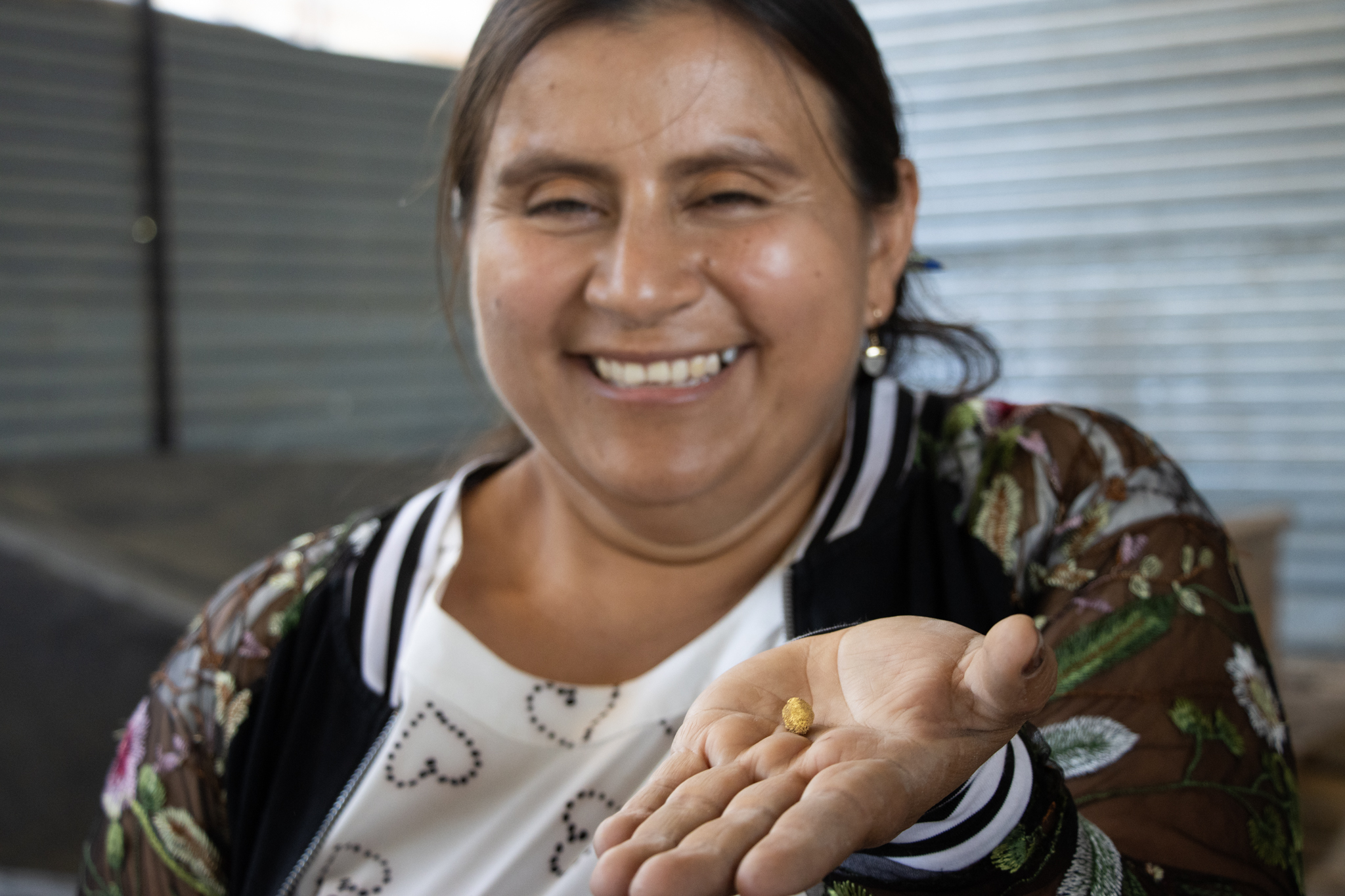 Mujer sonriendo, sosteniendo pepita de oro