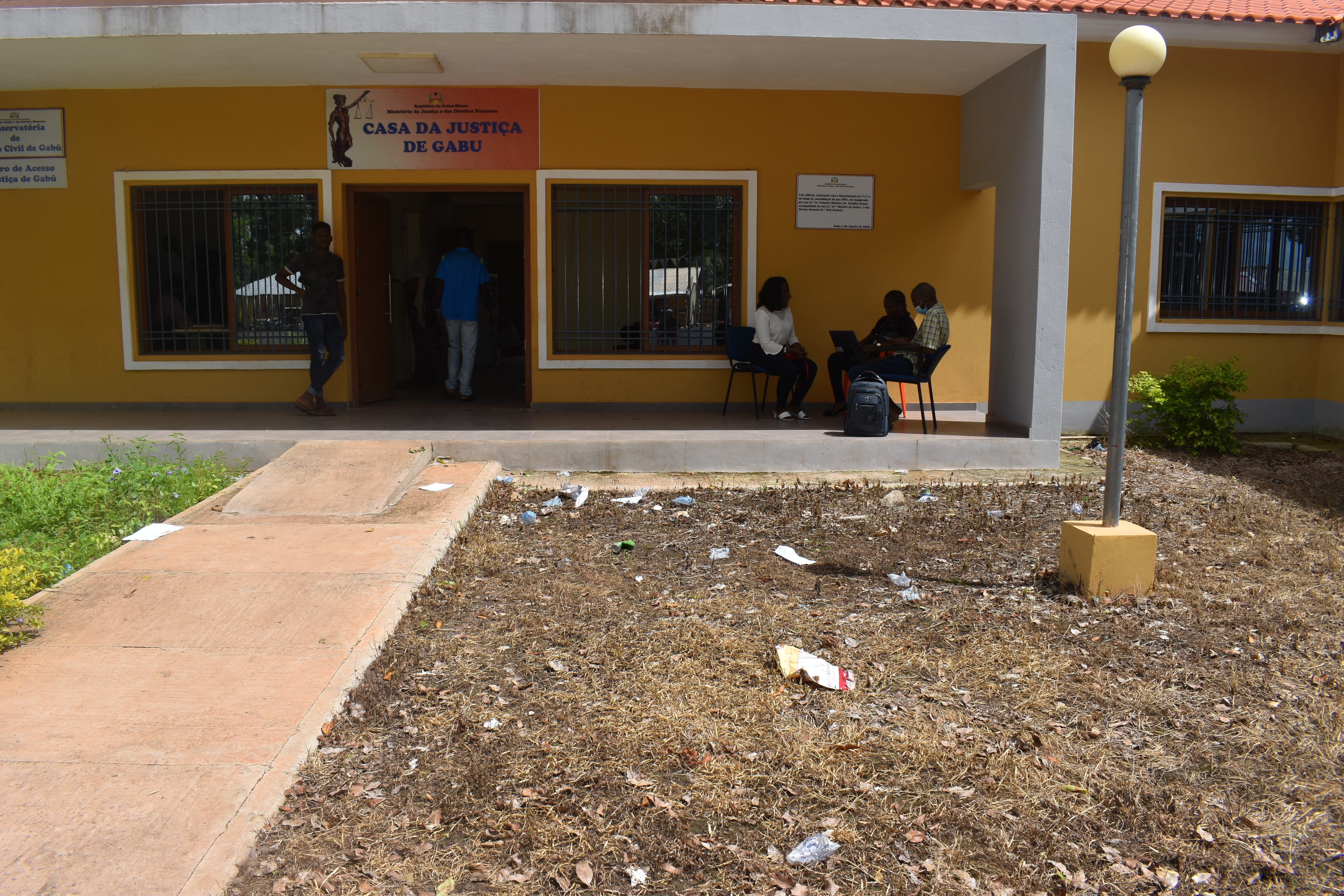 A falta de pontos de coleta de lixo resultou em um ambiente com lixo cobrindo o terreno. Casa de Justiça em Gabu.