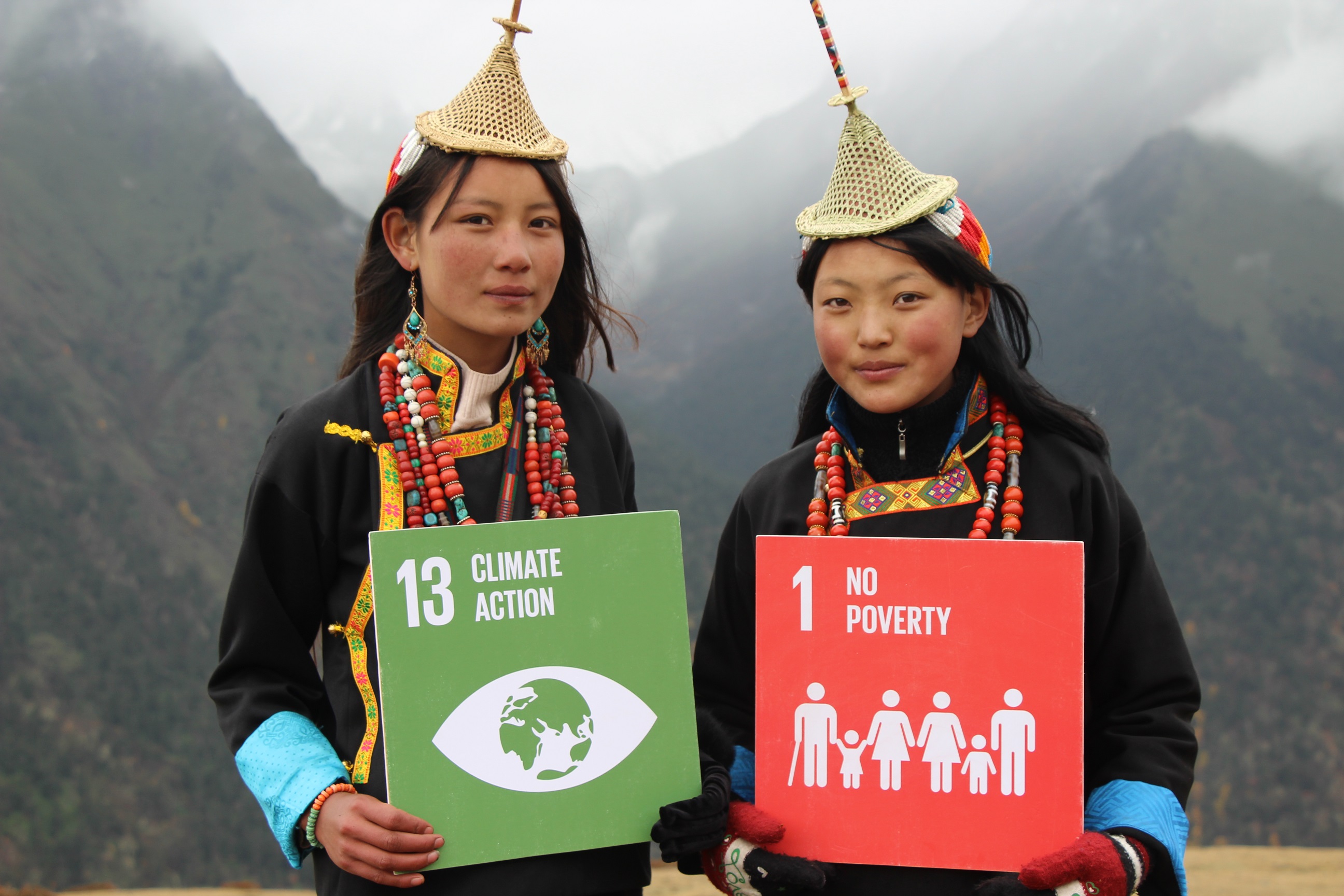 Women in Nepal holding 'climate action' and 'no poverty' signs.