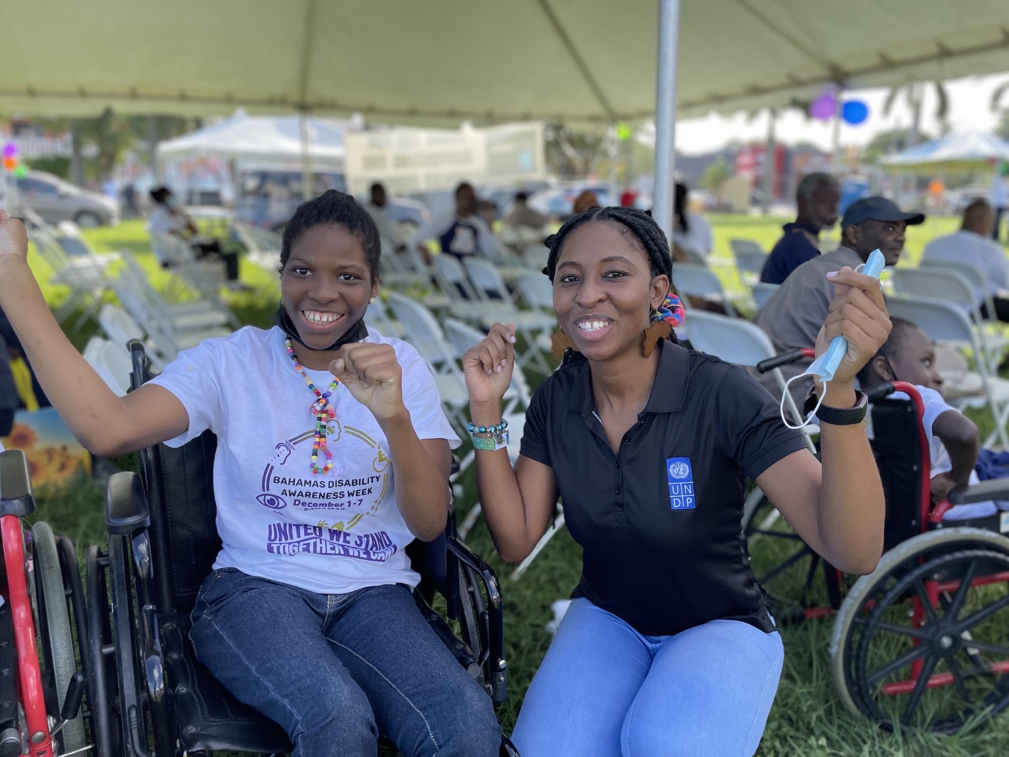 UNDP Team member poses with a happy young lady in a wheelchair at a Disabilities Week Concert and Motorcade in The Bahamas
