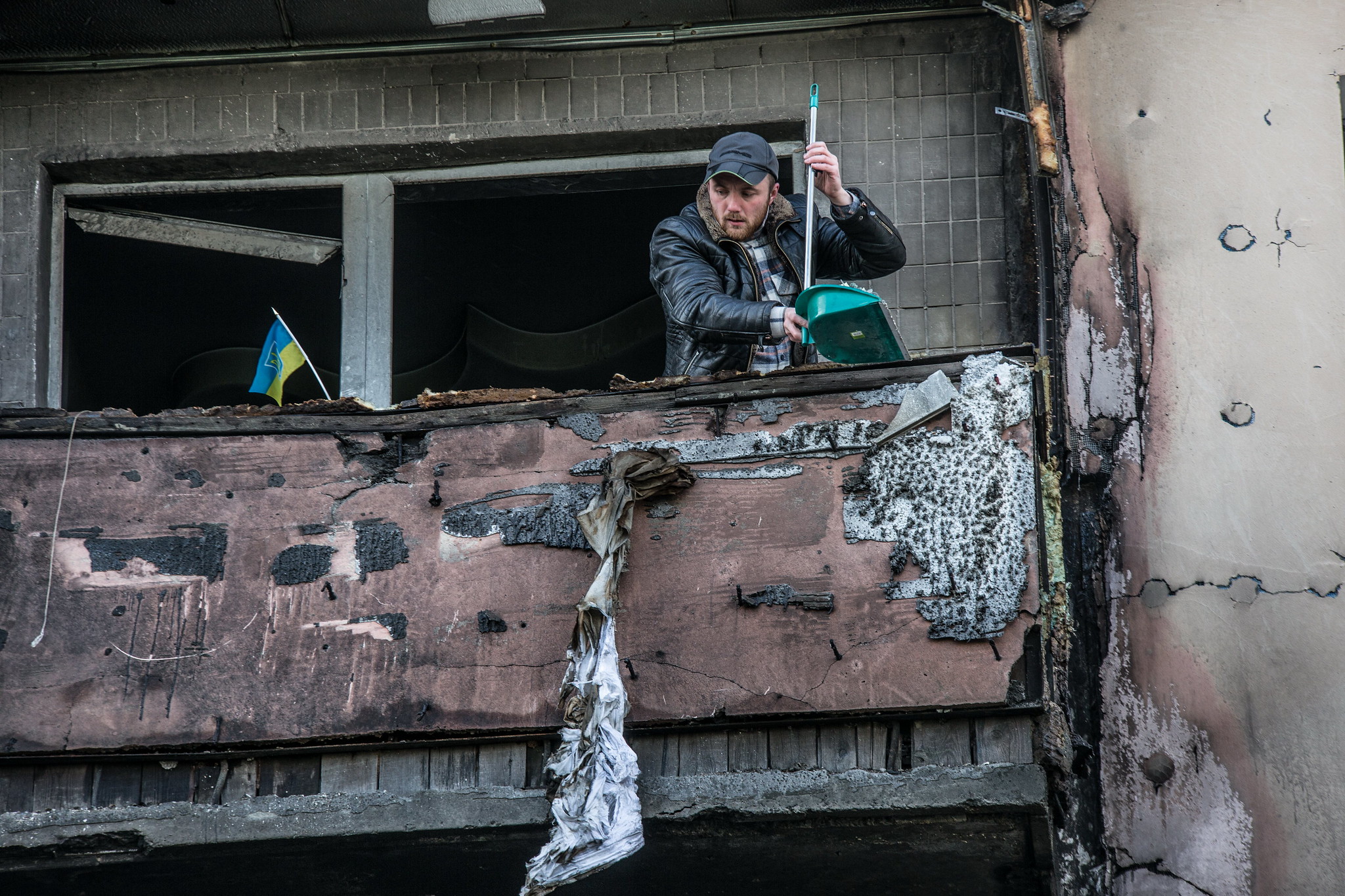 A man clears rubble from the balcony of an apartment damaged by shelling.