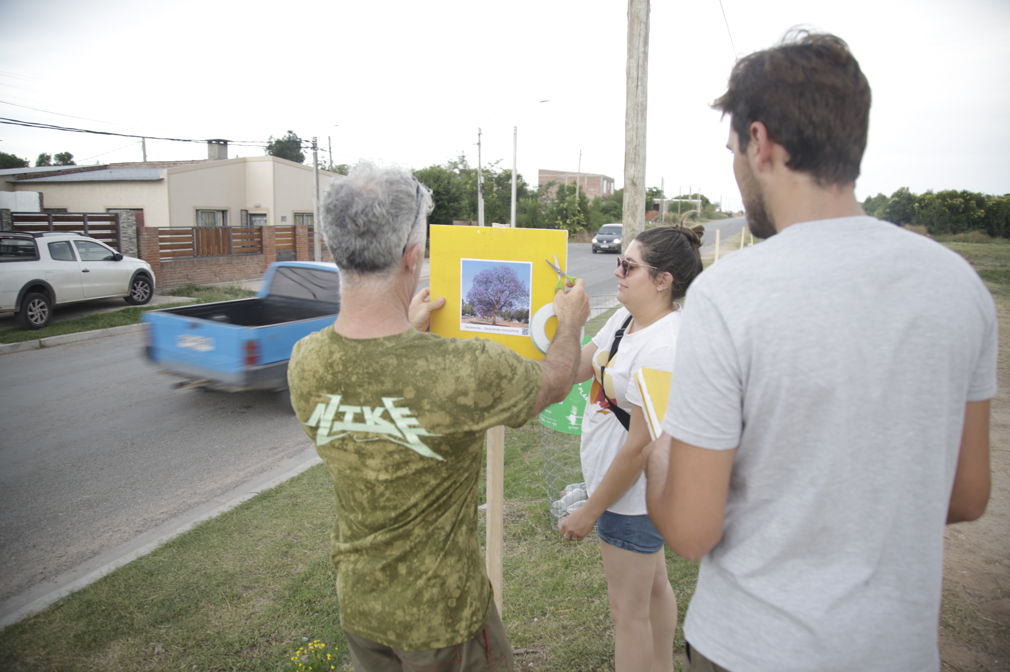 Tres jóvenes observan cartulina con diseño de propuesta de diseño para soluciones en plaza de Fray Bentos