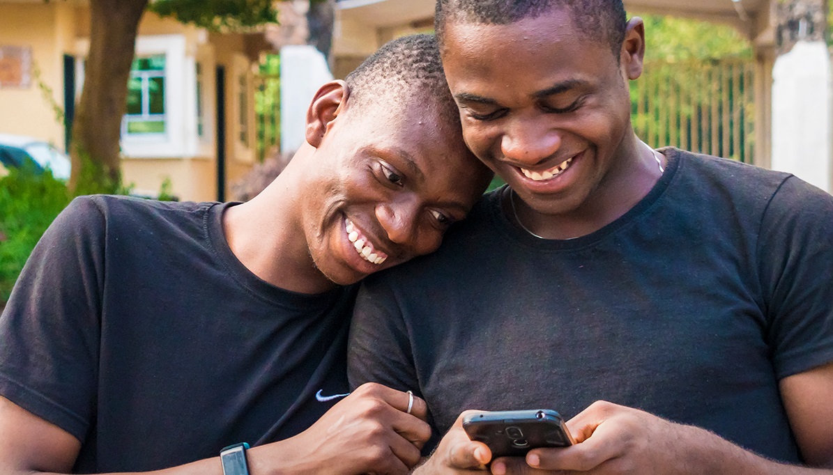 Two men smiling while looking at a mobile phone
