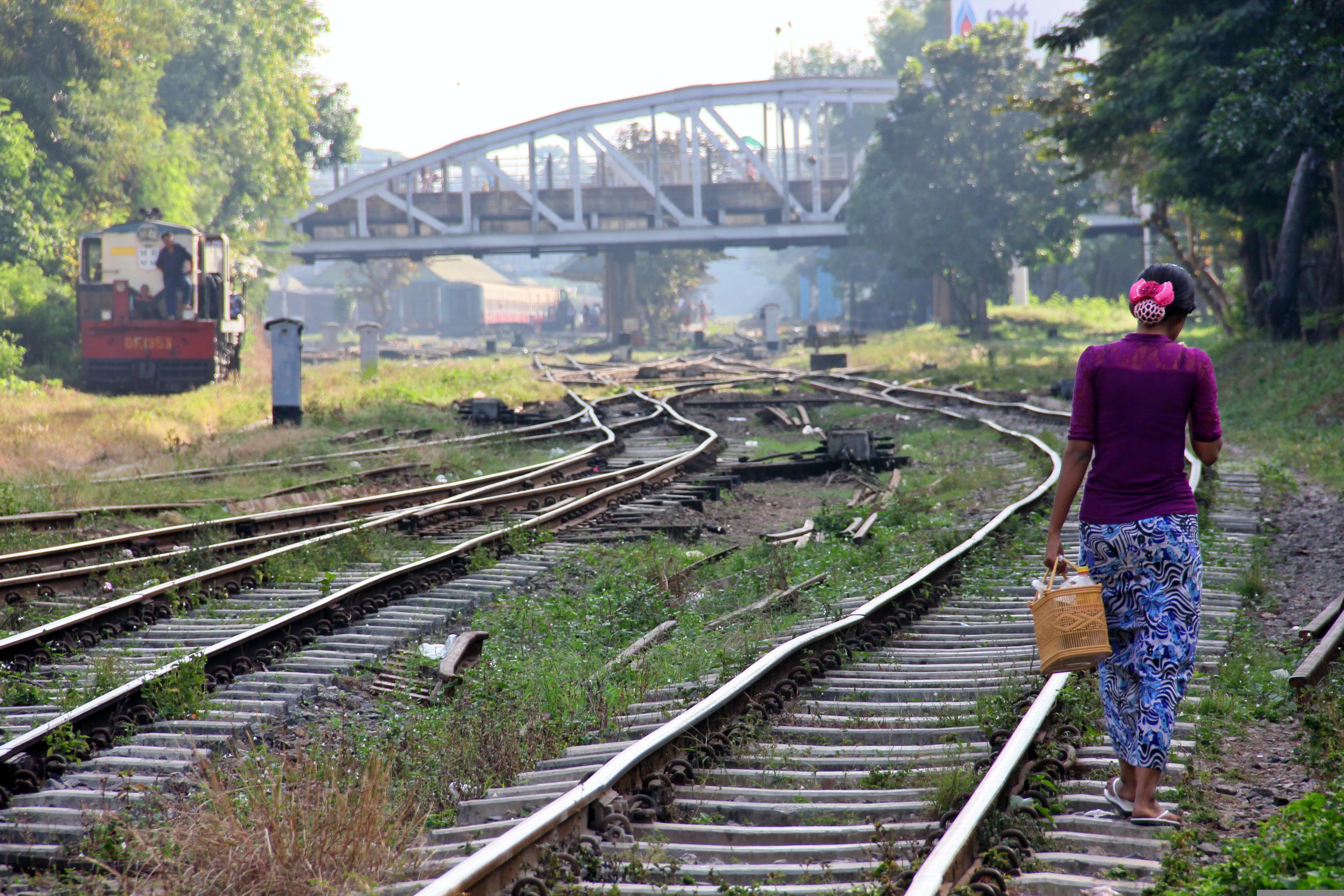 A woman walks along a train track in Yangon, Myanmar