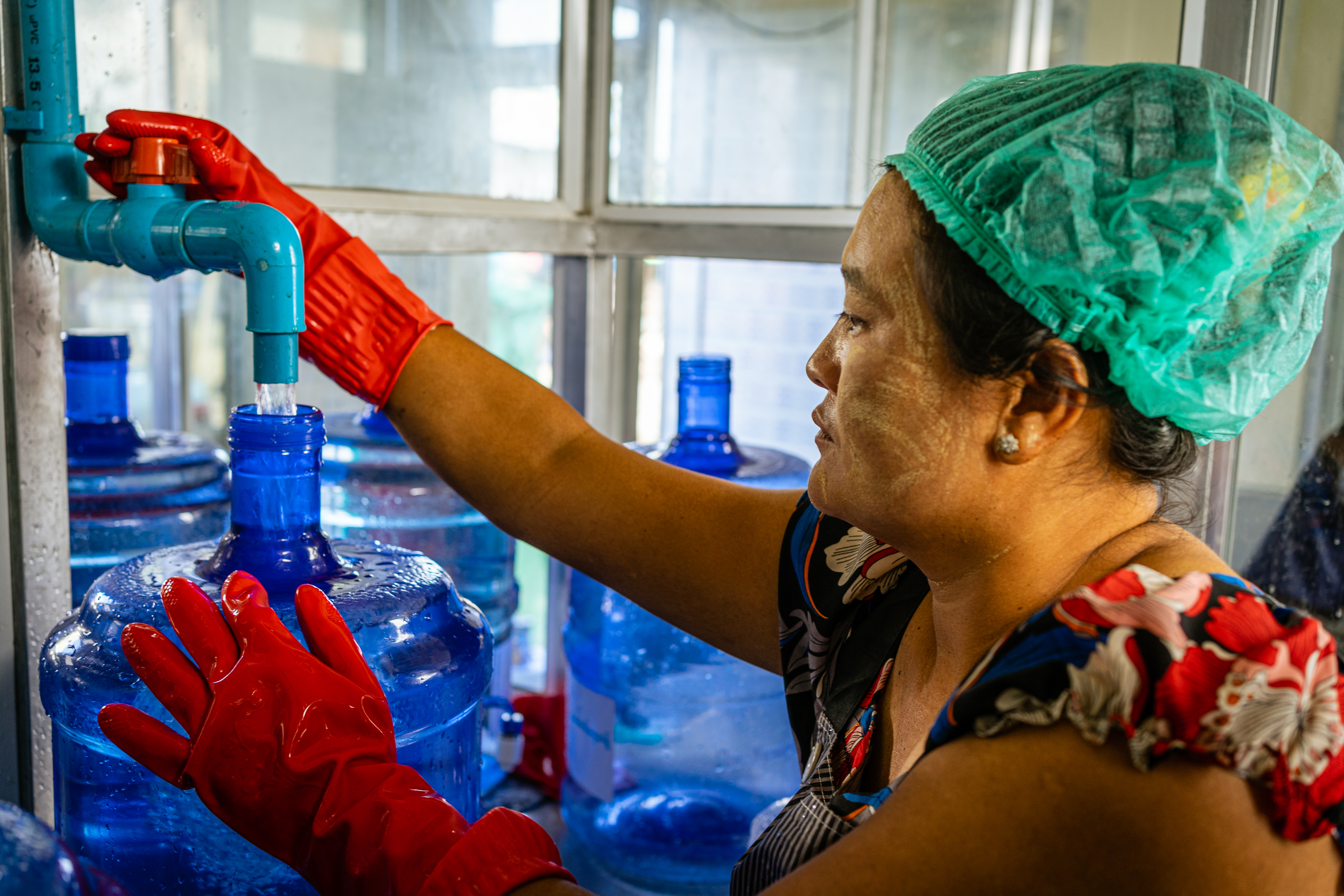 Ma Lin Lin fills a bottle with clean drinking water at the facility she leads in Yangon's Hlaingtharya Township (c) Ben Small/UNDP