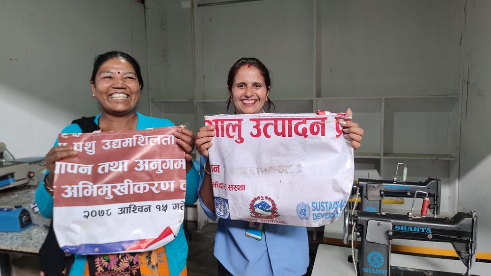 Two women with smile showing a flex banner with text