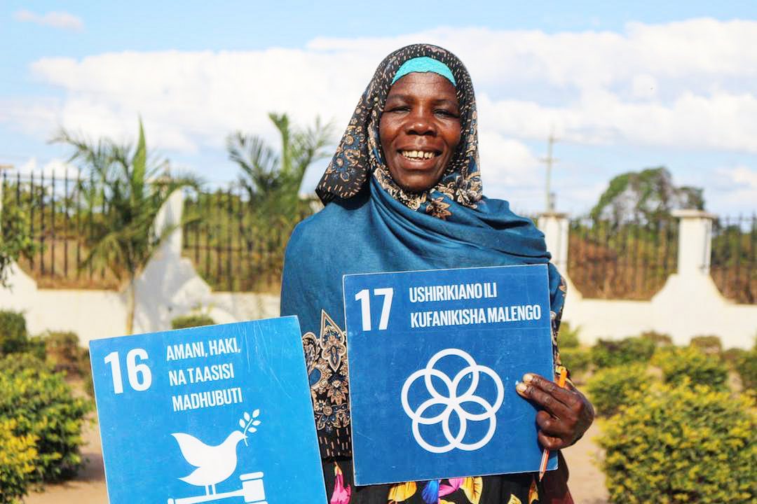 Woman holding two SDG signs