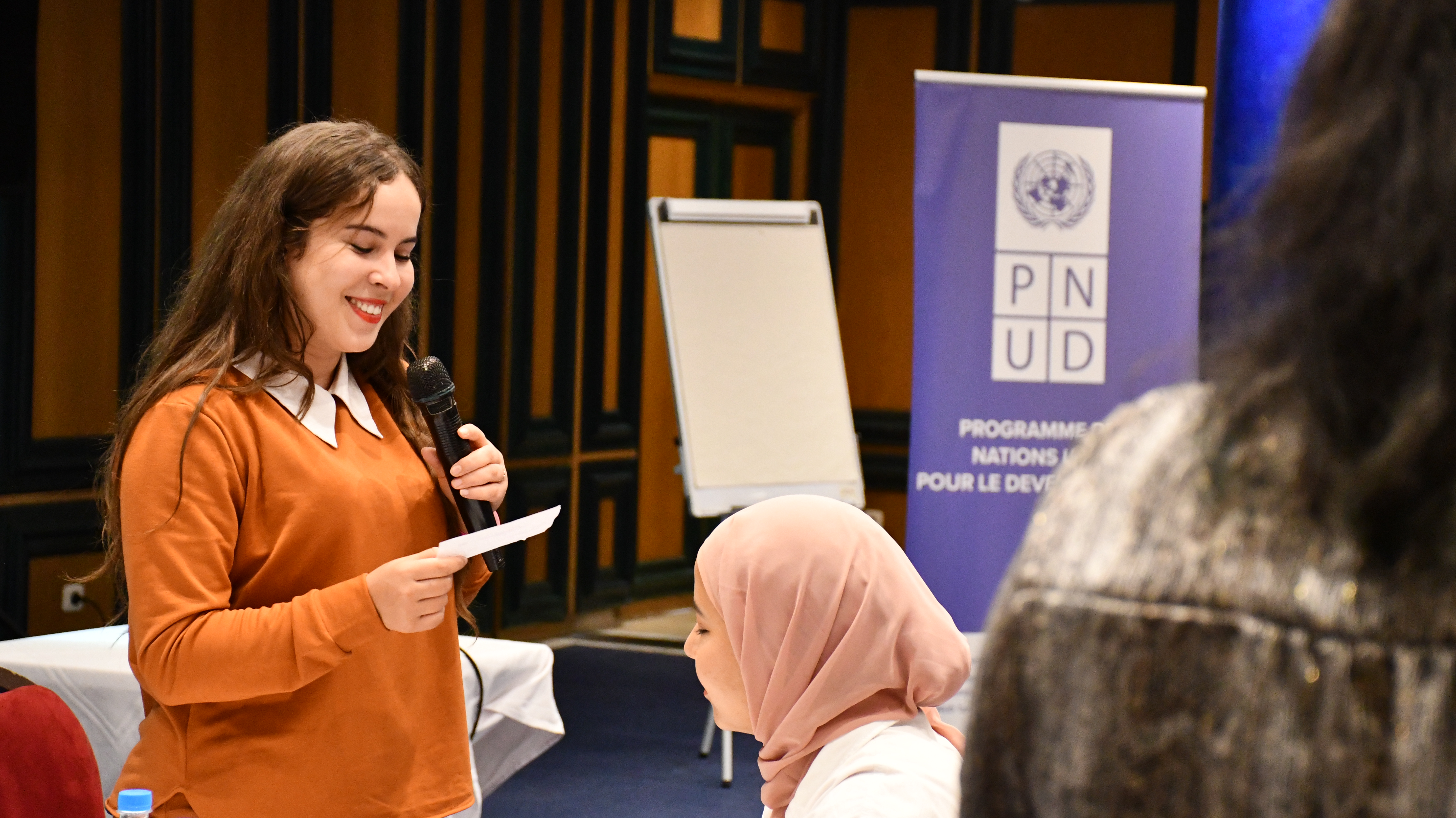 Jeune femme entrain de parler au micro devant un public jeune lors d'un workshop à djerba au sud tunisien afin de promouvoir sa région