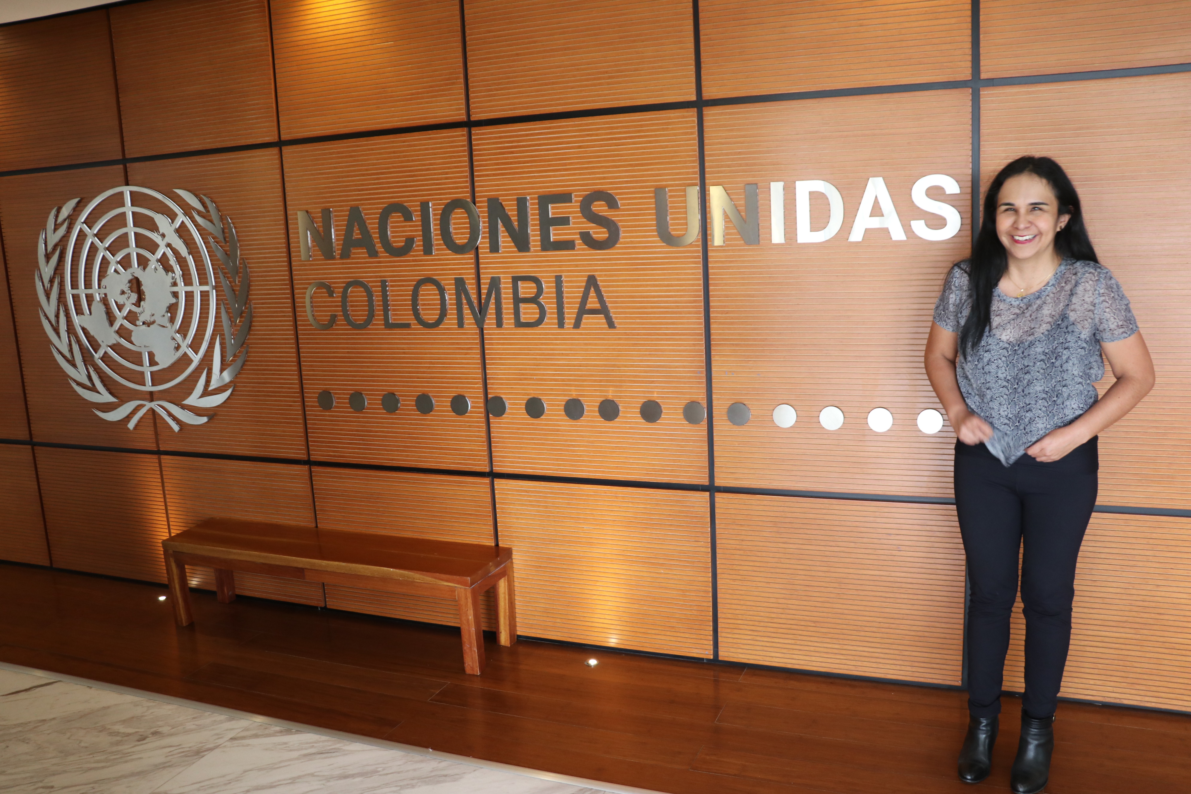 Adriana stands next to a sign that reads "Naciones unidas Colombia"