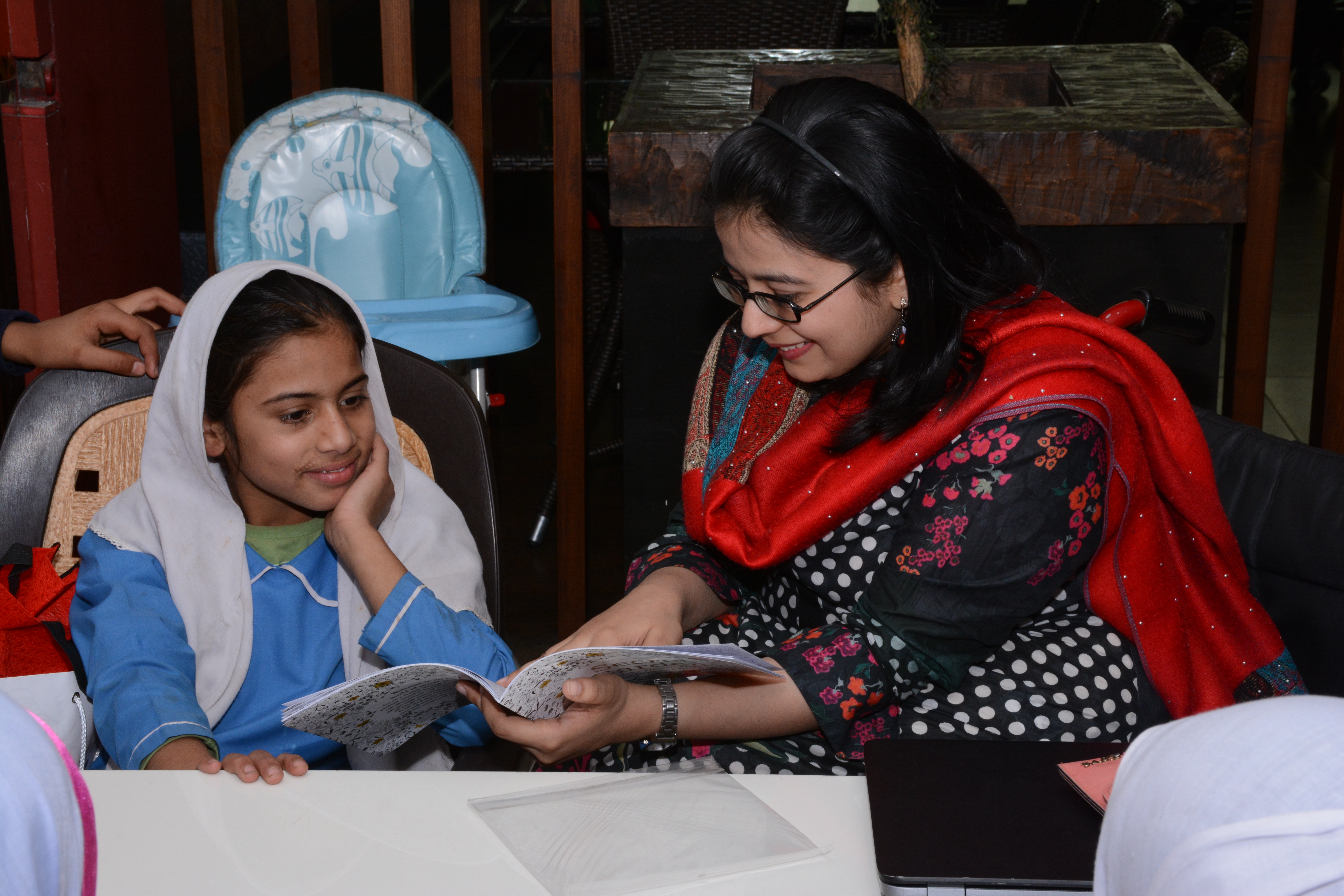 Tayyaba looks through a book with another young woman