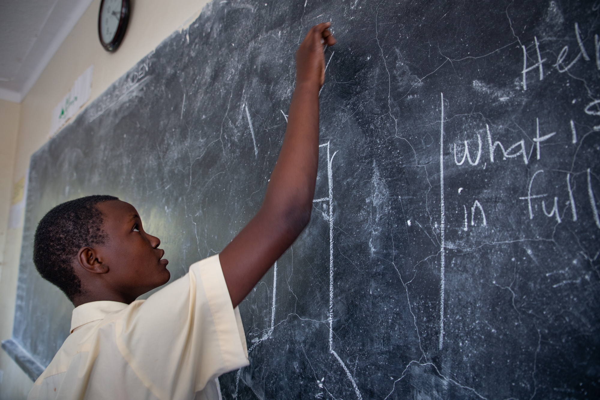 A student writing on a chalkboard in Kenya.