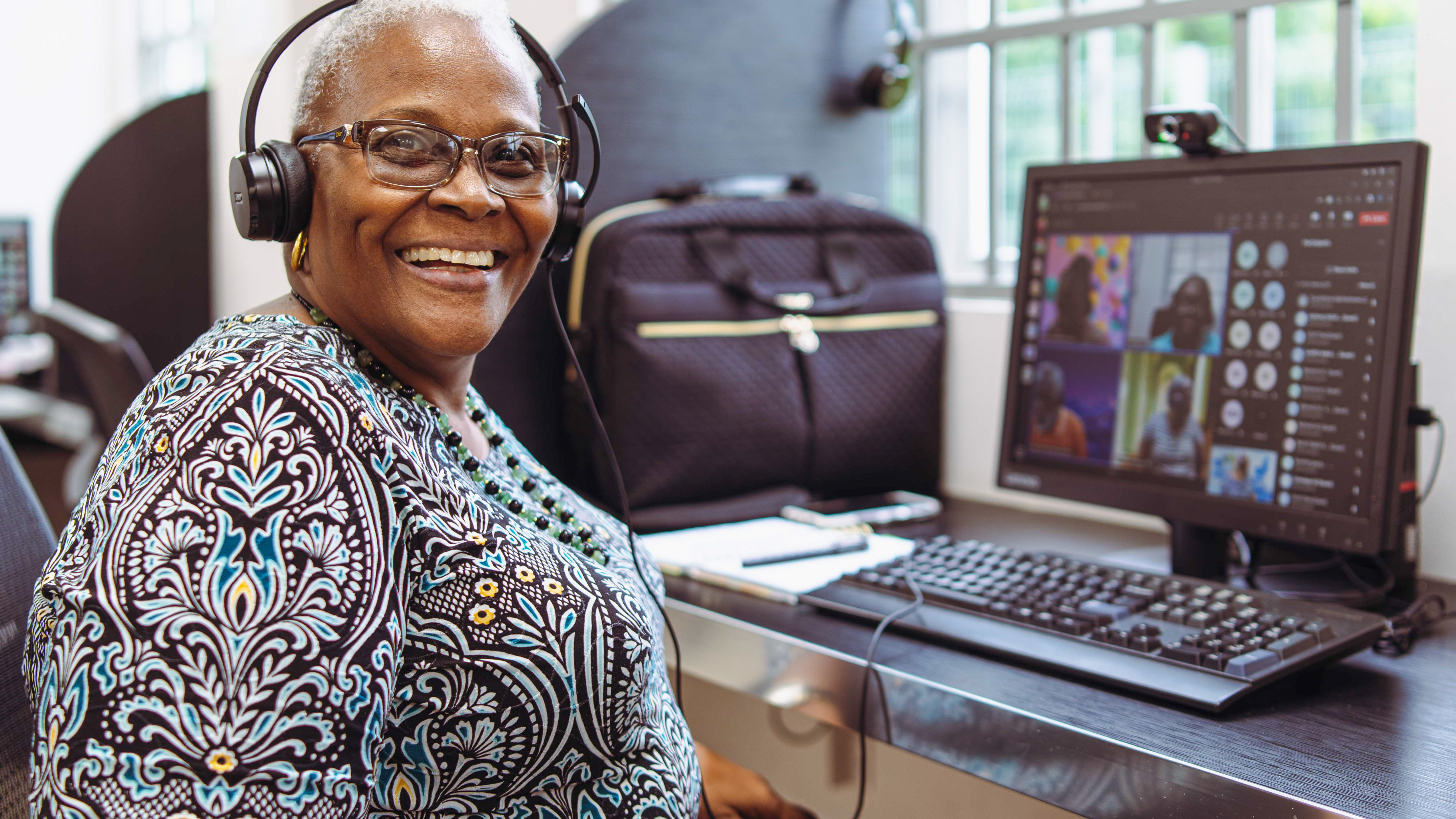 Woman wearing headphones sits at desktop computer