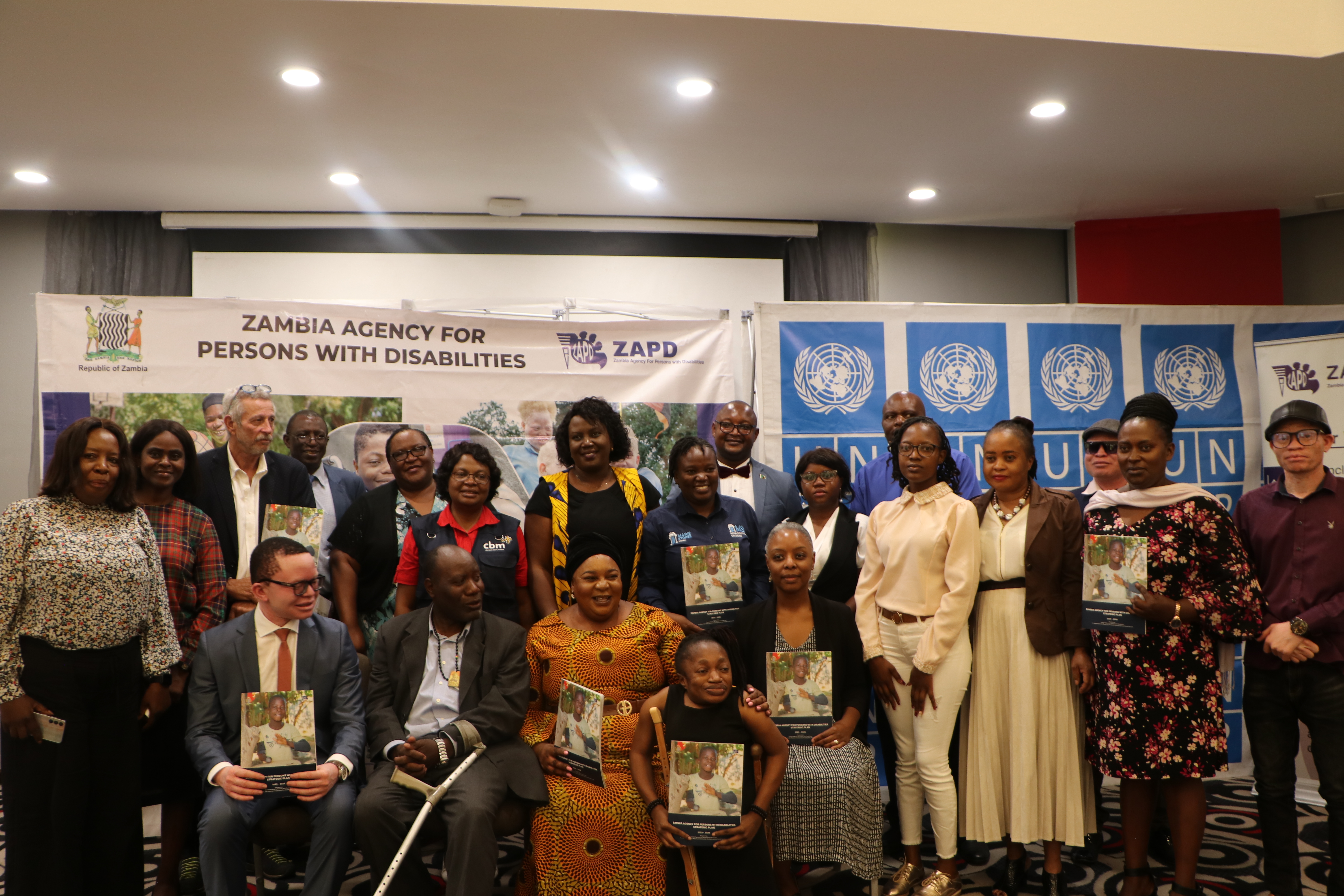 Image of the Minister of Community Development and Social Services and the Director General of ZAPD, joined by the UNDP and key partners at the Launch of the ZAPD Strategic Plan. They are all holding the strategic plan