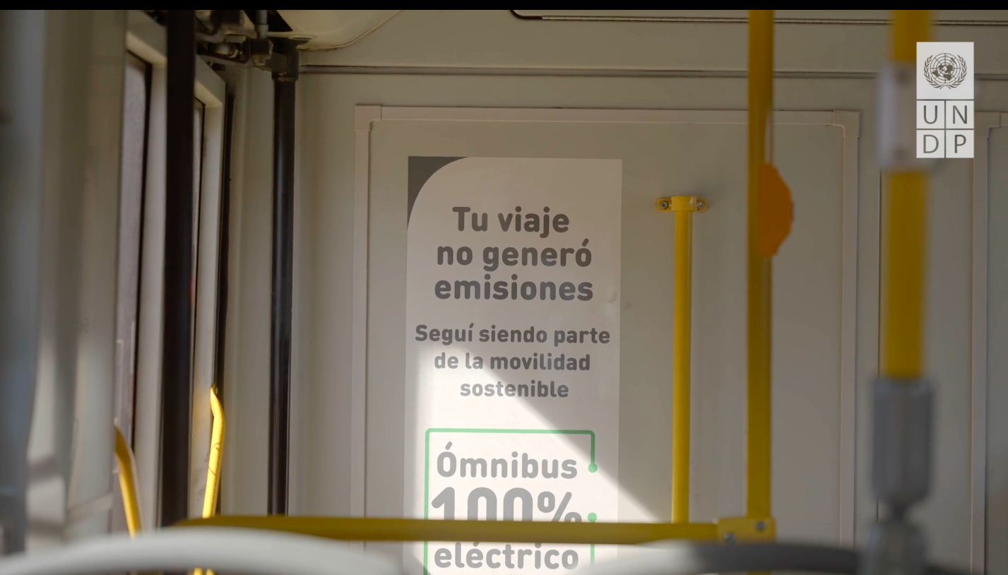 Foto interna de ómnibus en la que se lee un letrero con el siguiente contenido: "Tu viaje no generó emisiones. Seguí siendo parte te la movilidad sostenible. "Ómnibus 100% eléctrico".