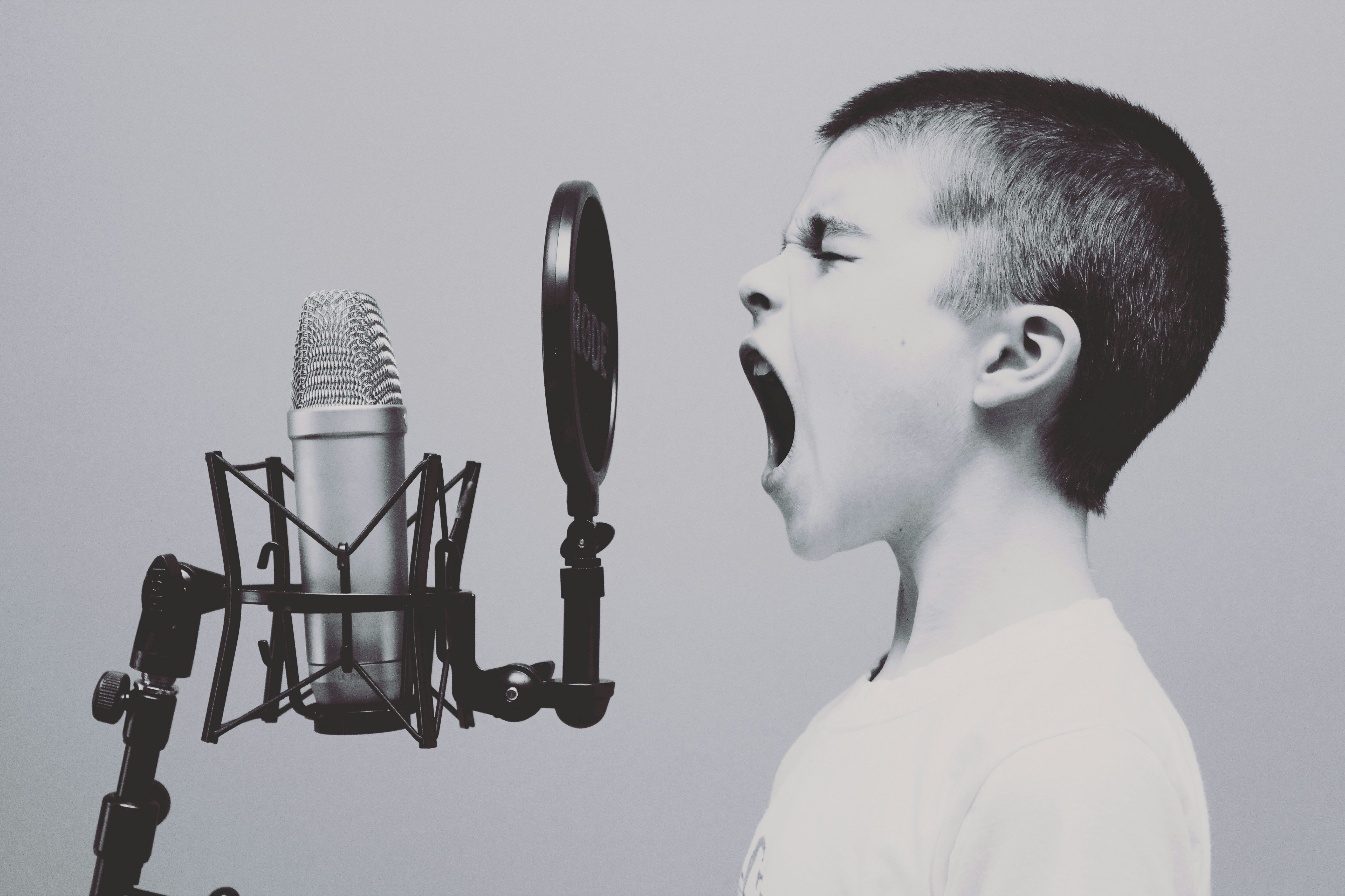 Black and white shot of young kid hollering into a microphone