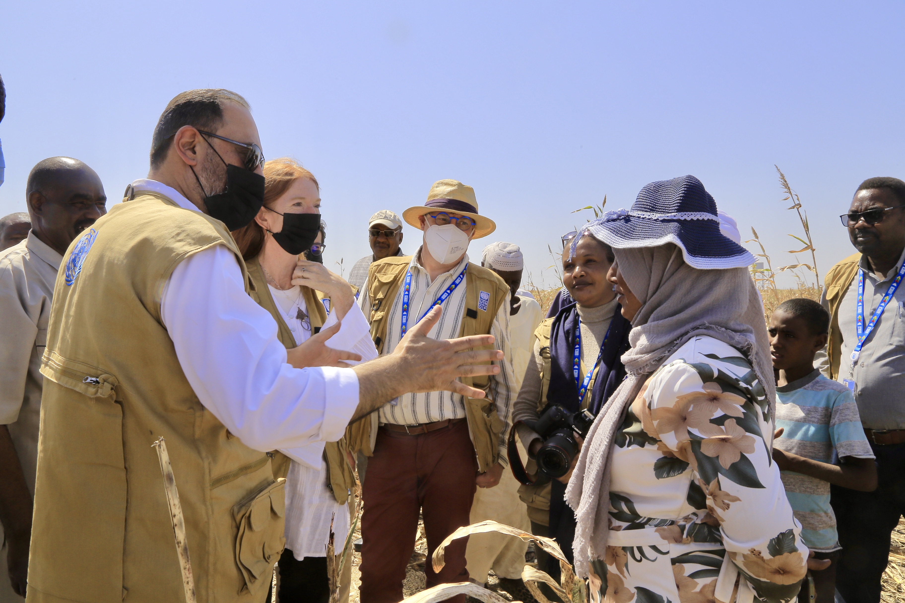 Man in facemask speaks to woman in hijab and sunhat