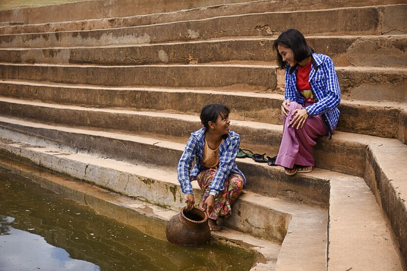 Two girls fetching water from the revitalized pond  