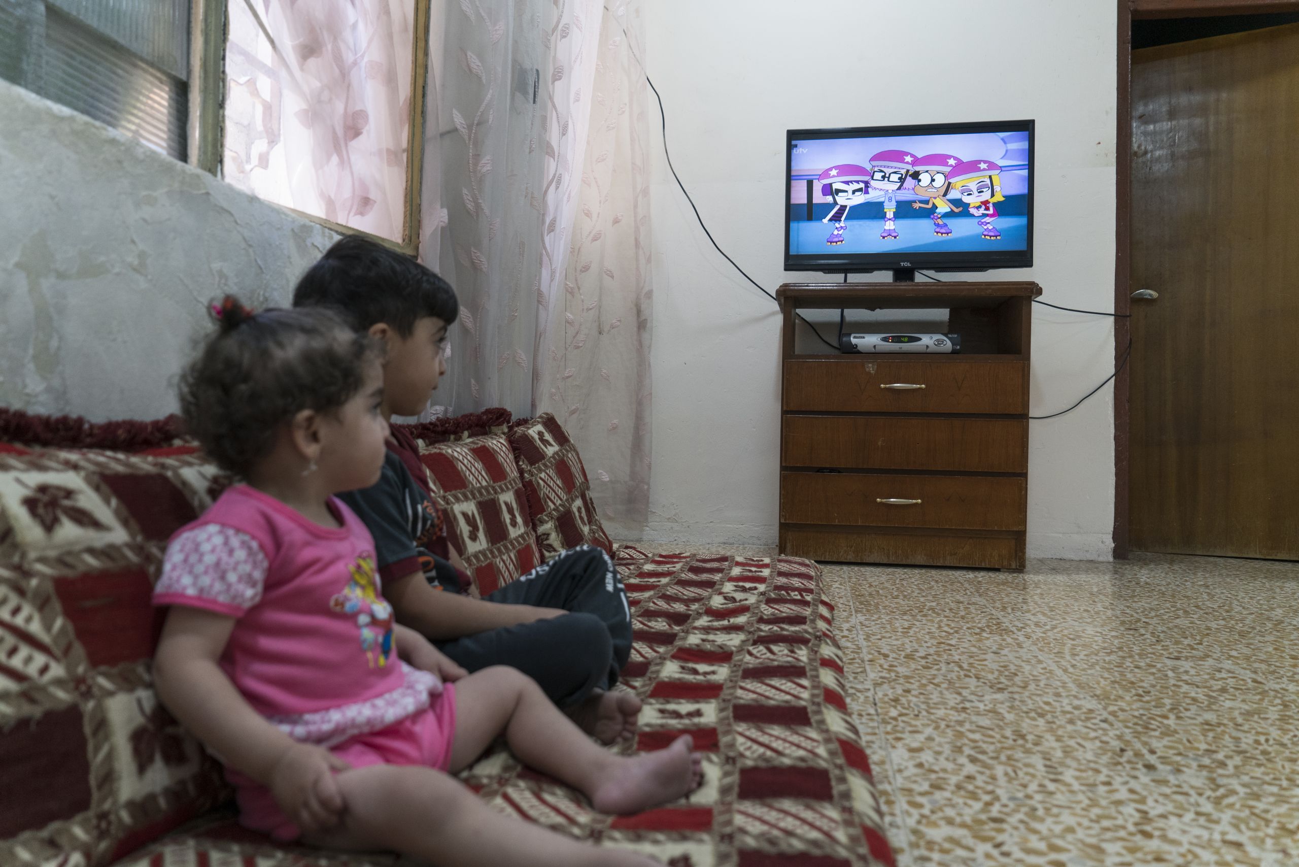 a little girl sitting on a couch playing a video game