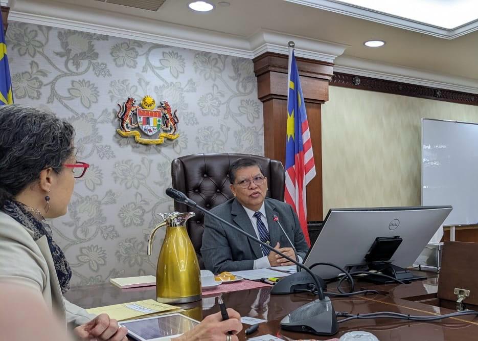 a person sitting at a table using a laptop computer