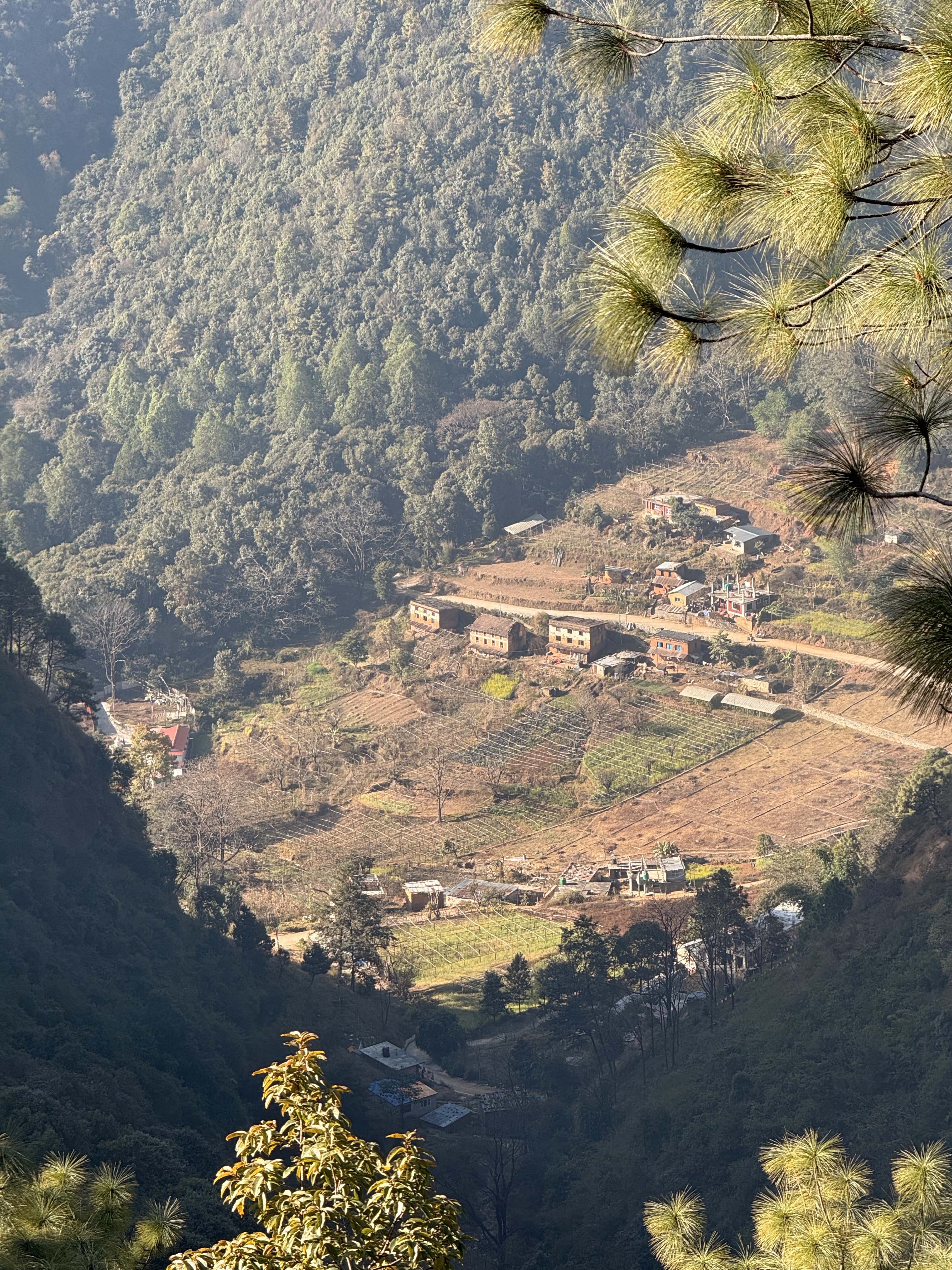 A panoramic view of a valley with scattered houses surrounded by mountains.