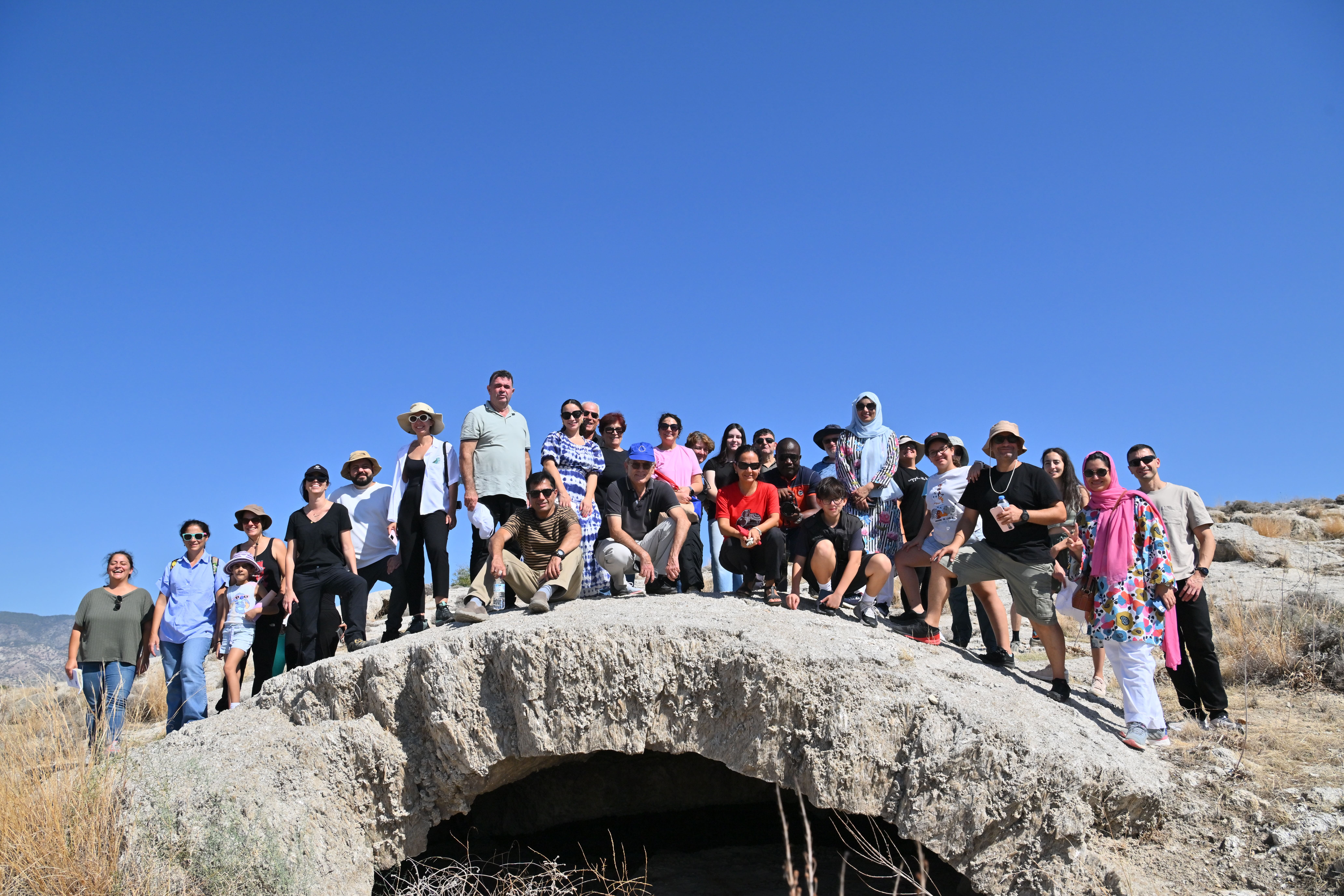 A large group of people posing together outdoors against a clear blue sky.