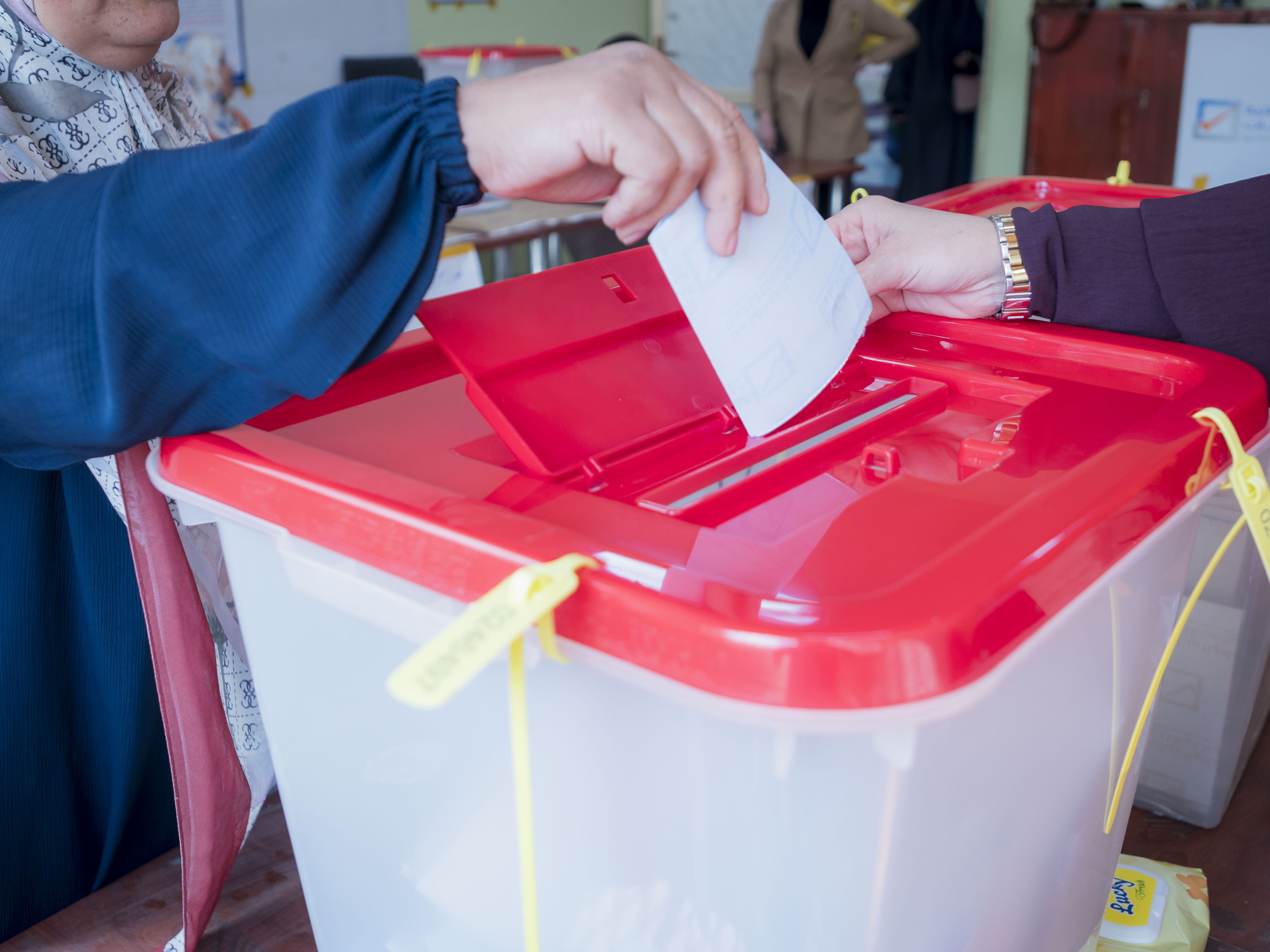 Woman placing a ballot into voting box.