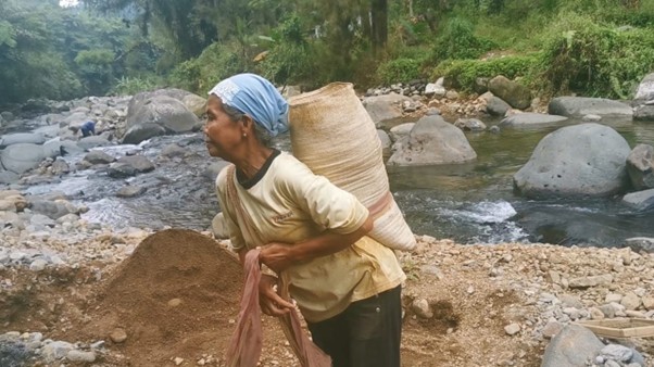 Saumi carries a sack of sand along the riverbank in Tinalum. With fewer farming options due to drought, sand mining became one of the only sources of income for women like her.