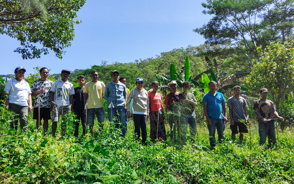 A group of people standing together on a hillside, surrounded by lush greenery and trees.