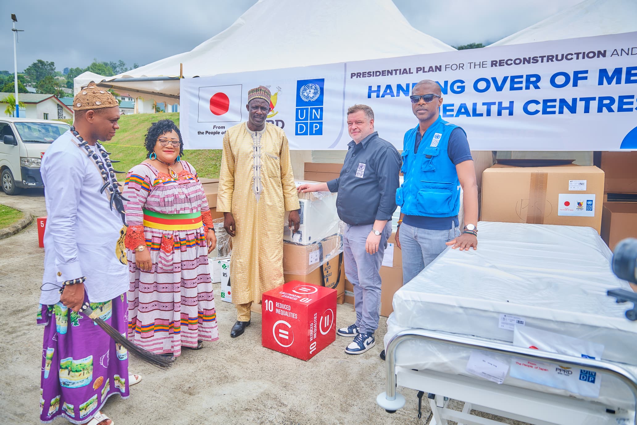 Group of people at a healthcare center, handing over medical supplies, smiling and engaged.