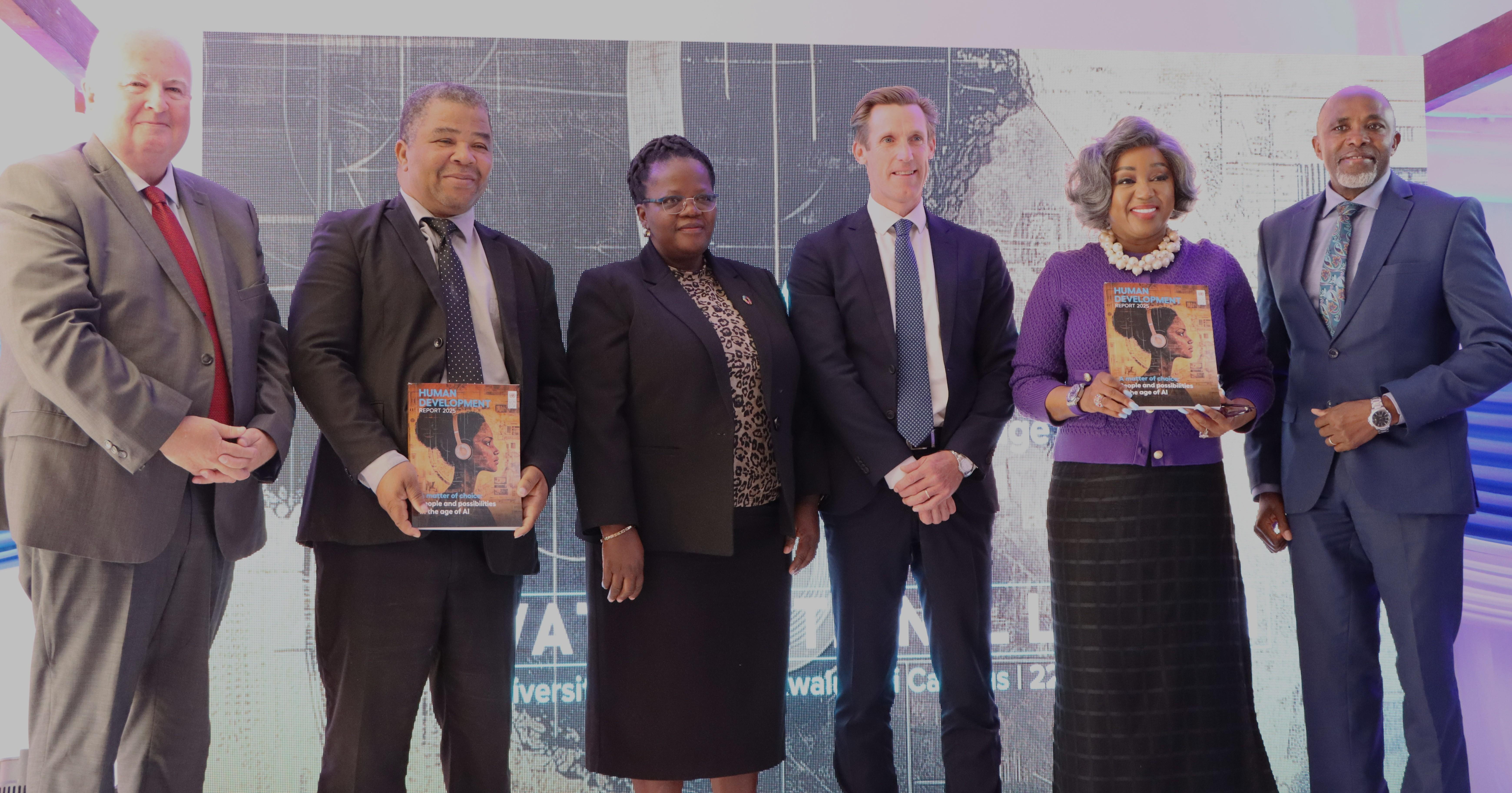 Six people standing together, holding books, in a modern studio setting.