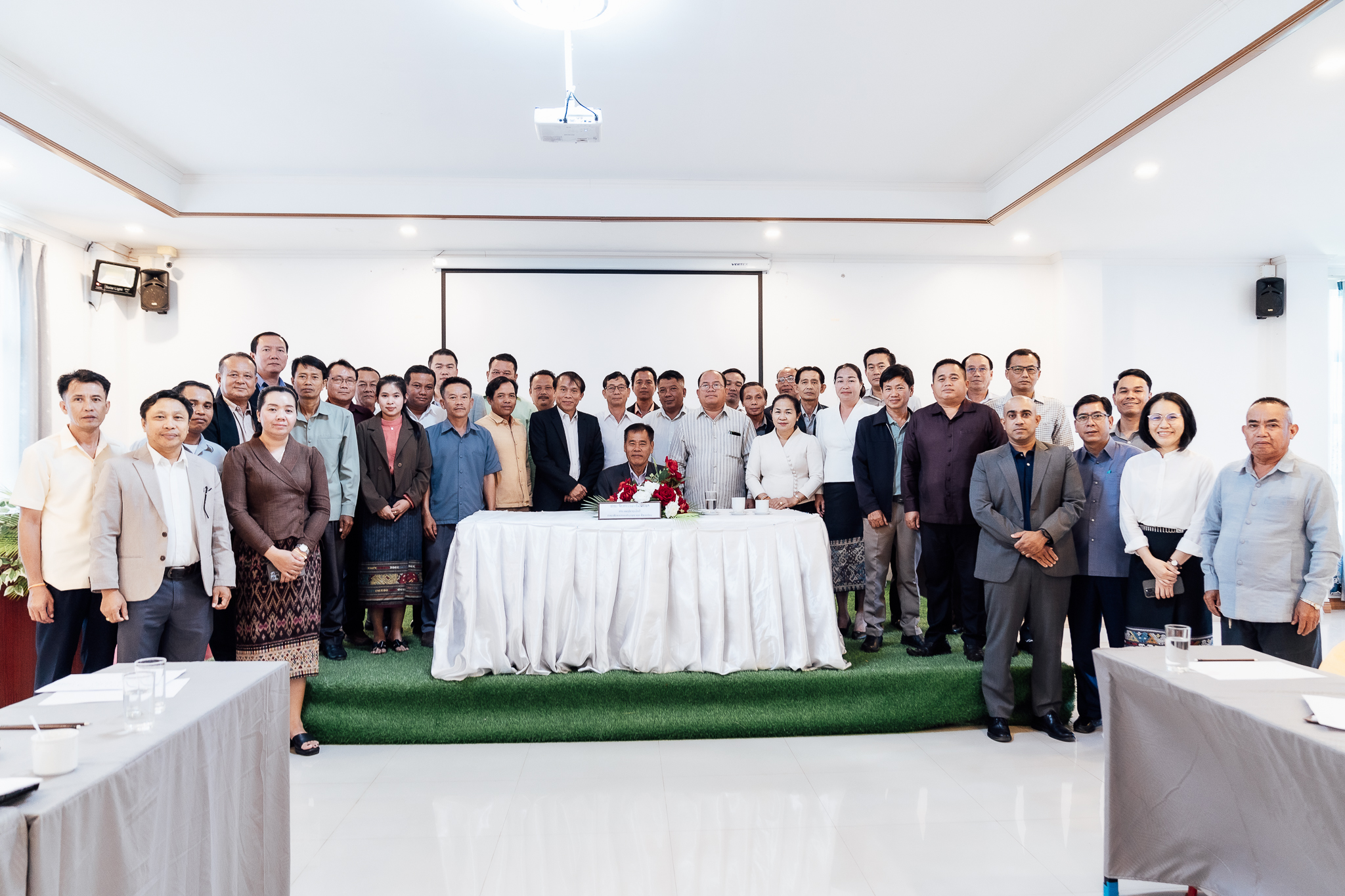 Group photo of individuals gathered around a table in a conference room setting.