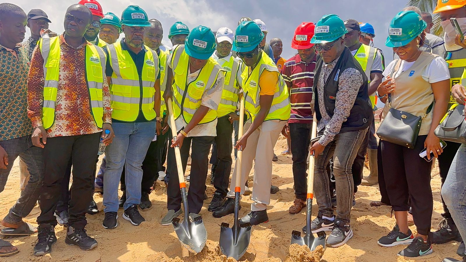 Group of people in safety vests and hats participating in a groundbreaking ceremony.