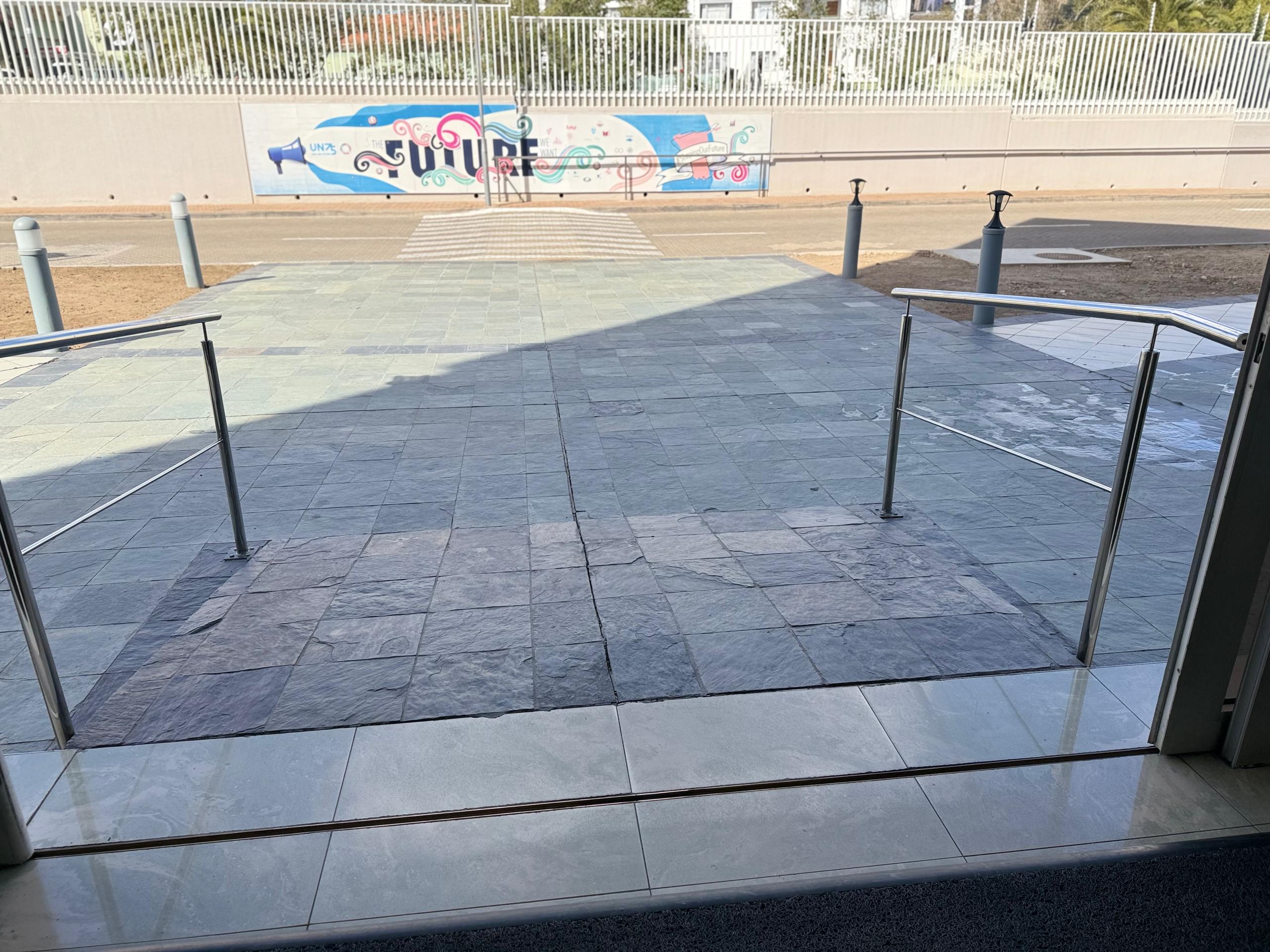 View from an entrance showing a sloped pathway and railings leading outside.