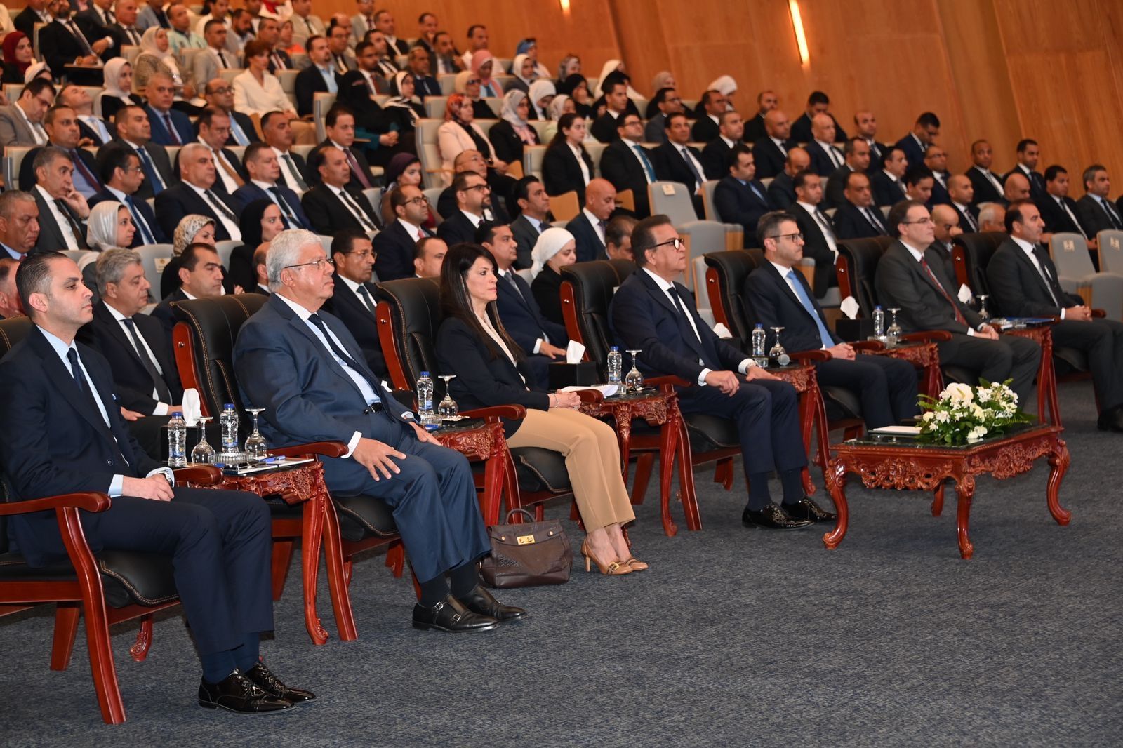 A large audience seated in a conference hall, facing speakers on stage.