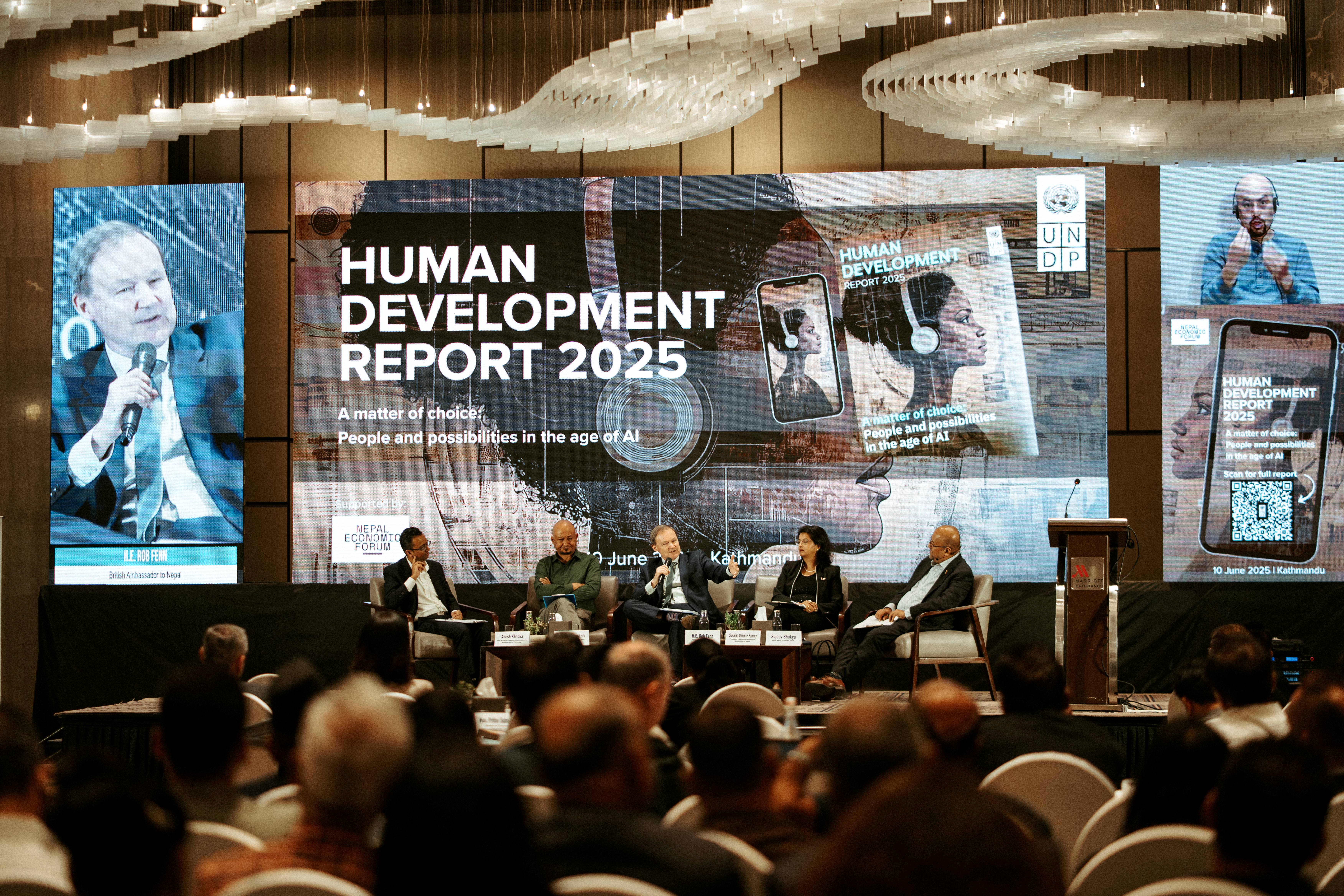 Panel discussion at a conference with speakers and a large screen displaying "Human Development Report 2025."