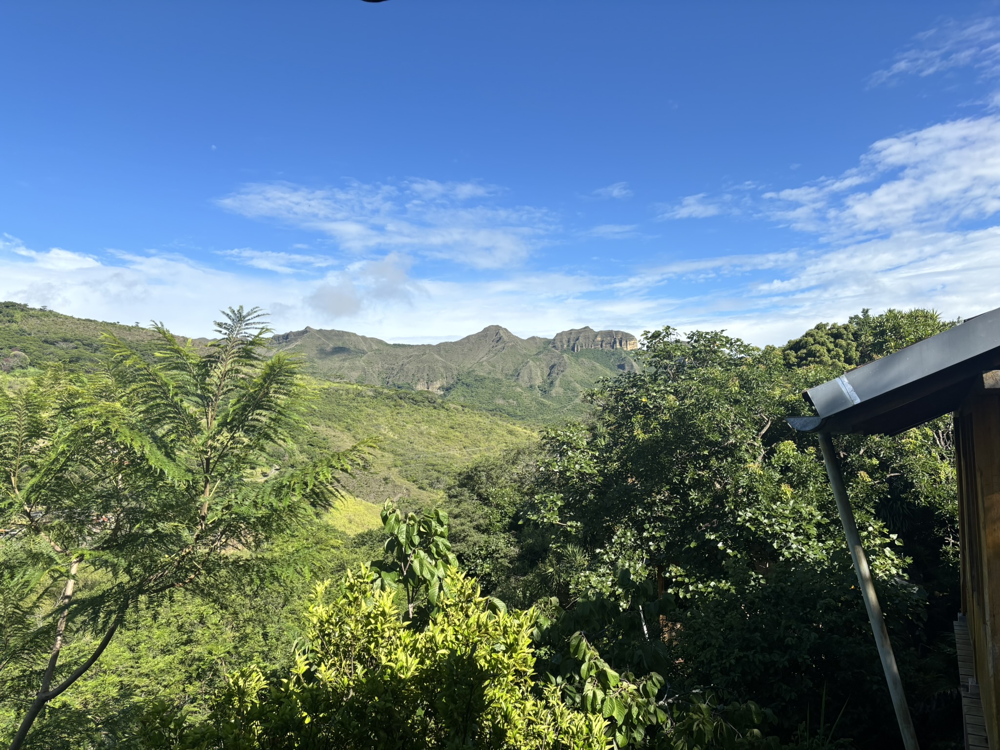 Lush green hills under a bright blue sky with scattered clouds.