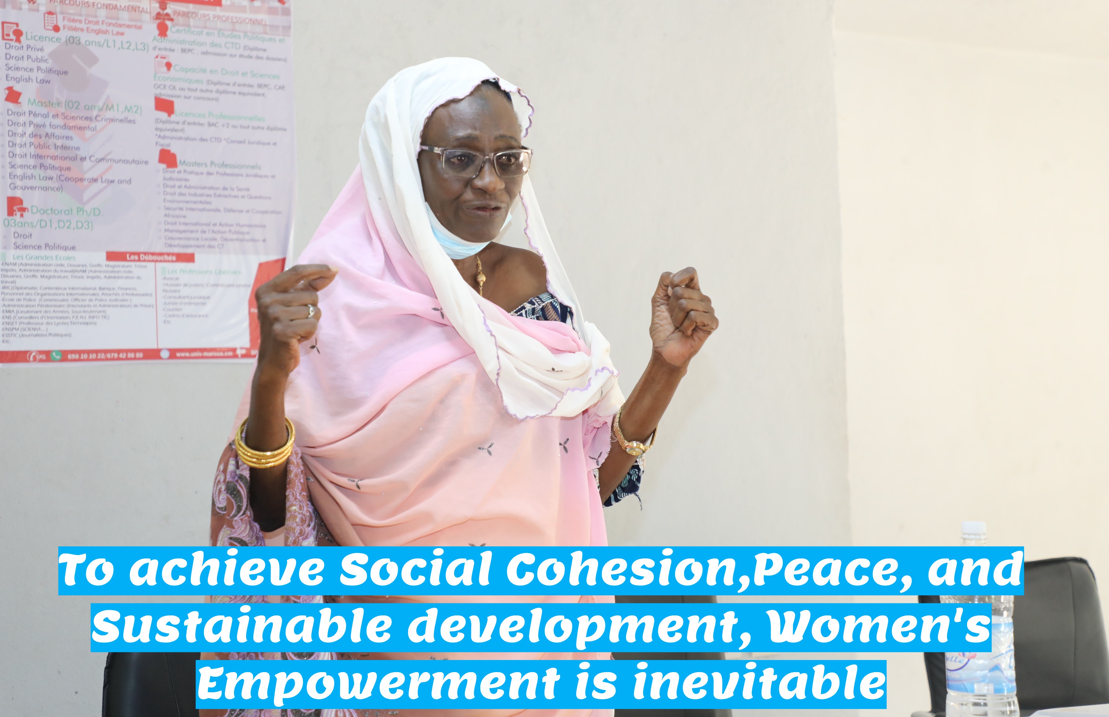 A woman in traditional attire, speaking passionately at an event, advocating for women's empowerment.
