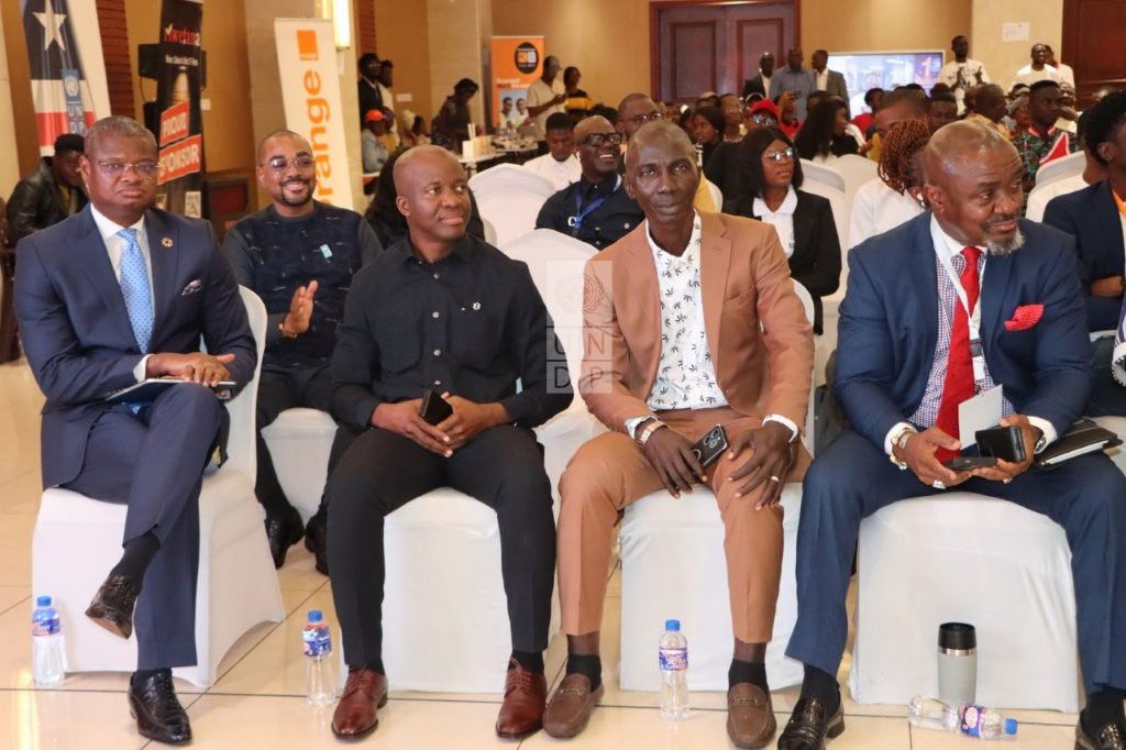Five men seated in a modern conference room, engaged and attentive.