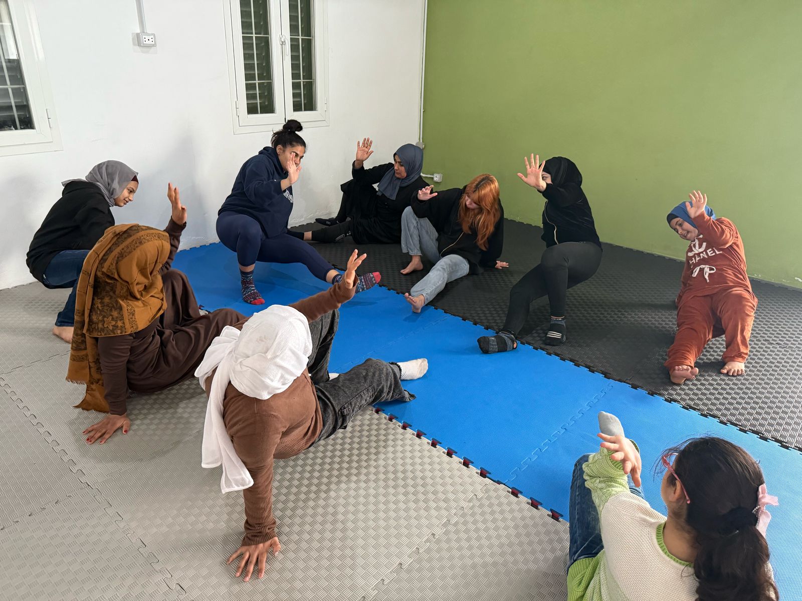 A group of people practicing a physical activity in a studio with blue mats.