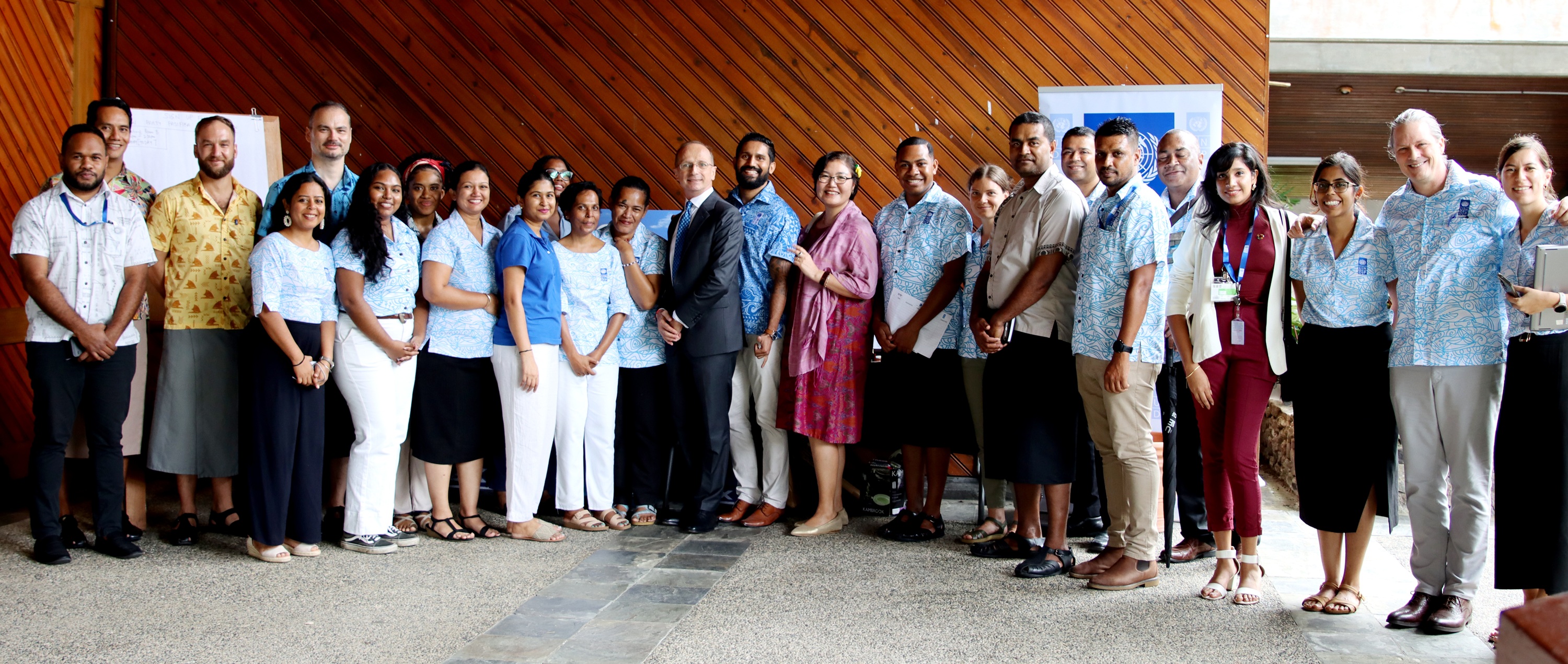 A diverse group of people posing together in a formal setting, smiling and engaged.