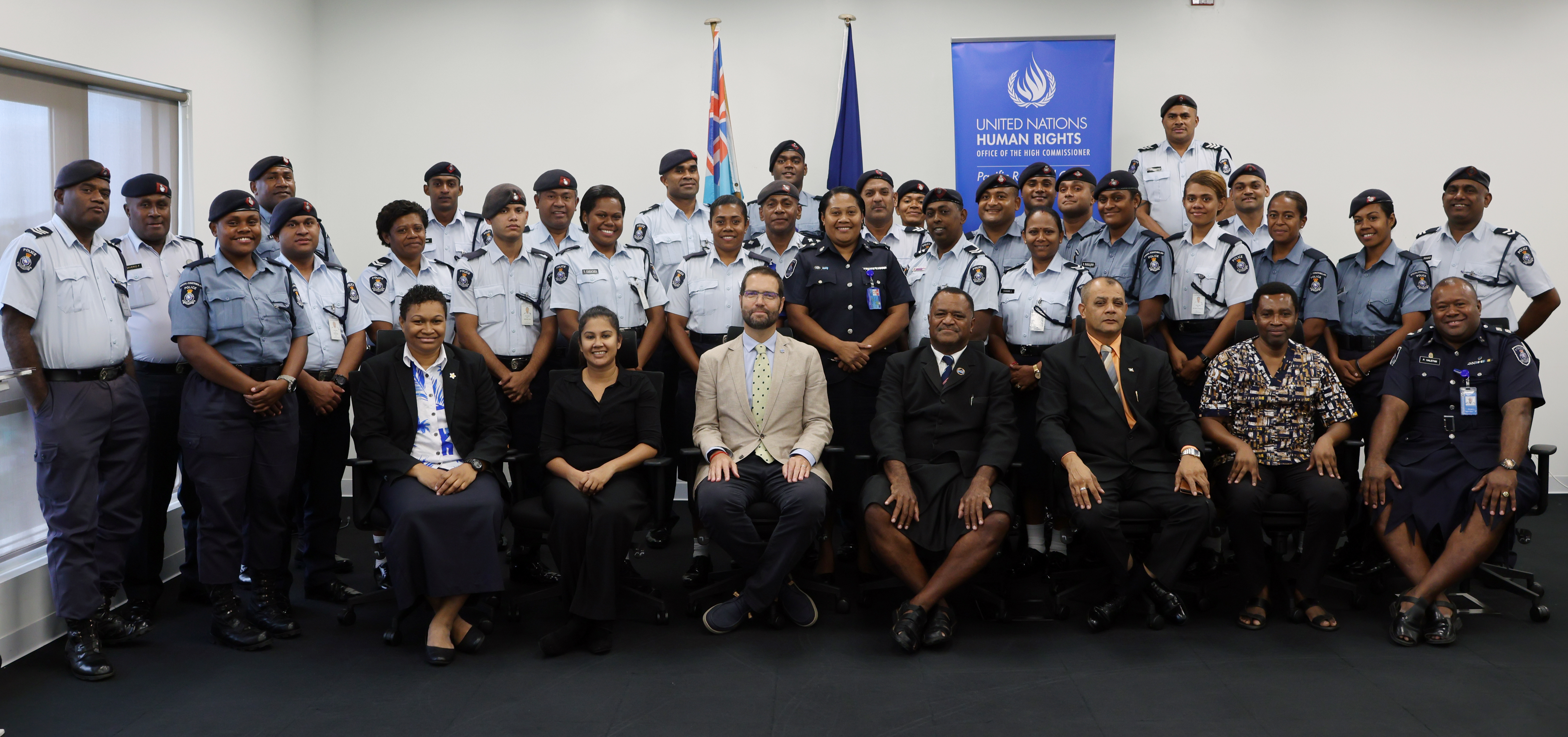 Group photo of uniformed police officers and officials in an indoor setting.