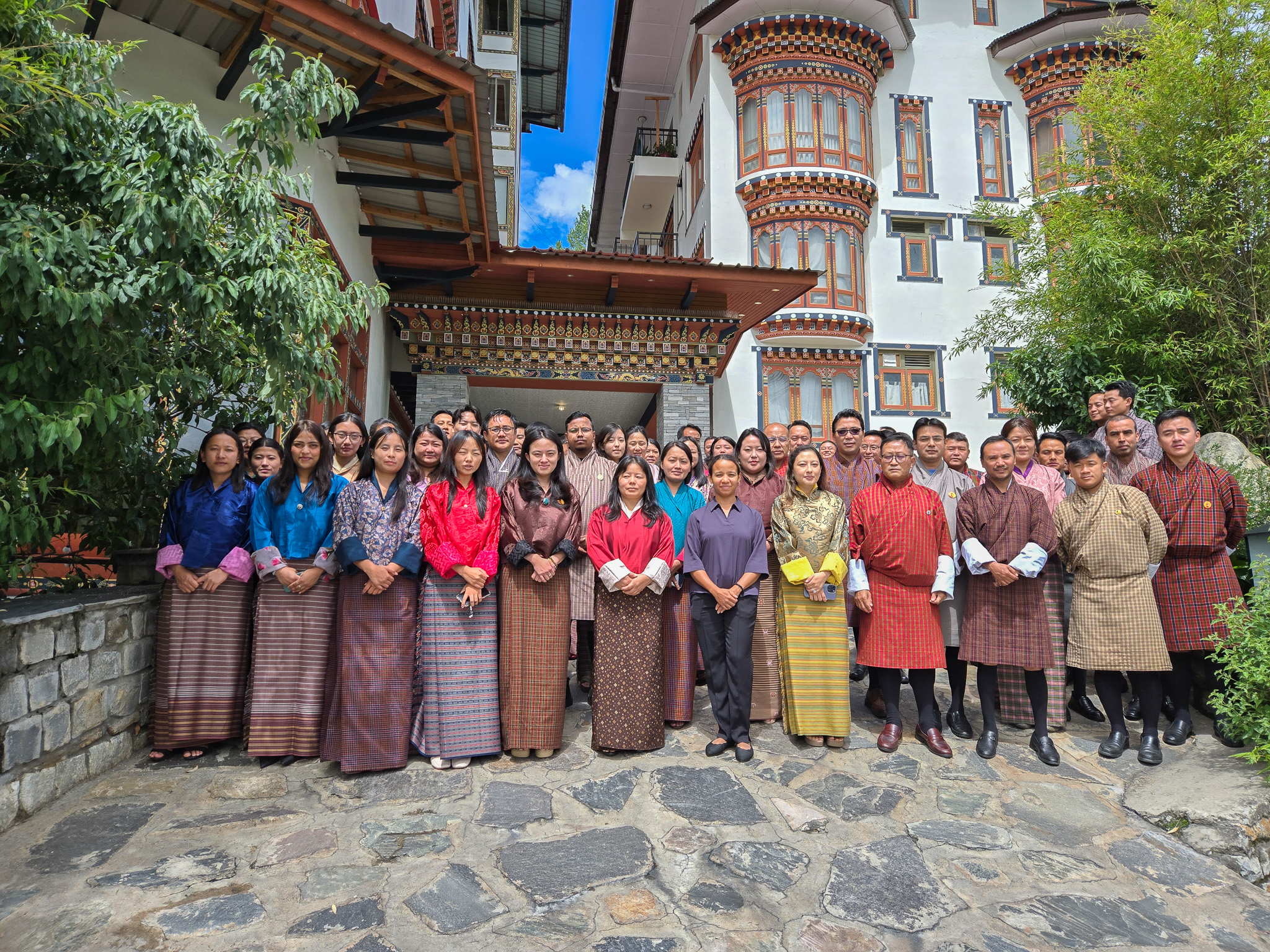 Group of people in traditional attire posing outdoors in front of a building.