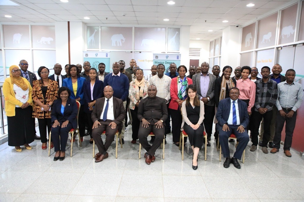 A large group of diverse people posing together in a modern office setting.