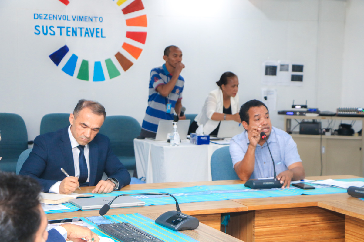 A group meeting in a conference room with seated participants and a presenter.